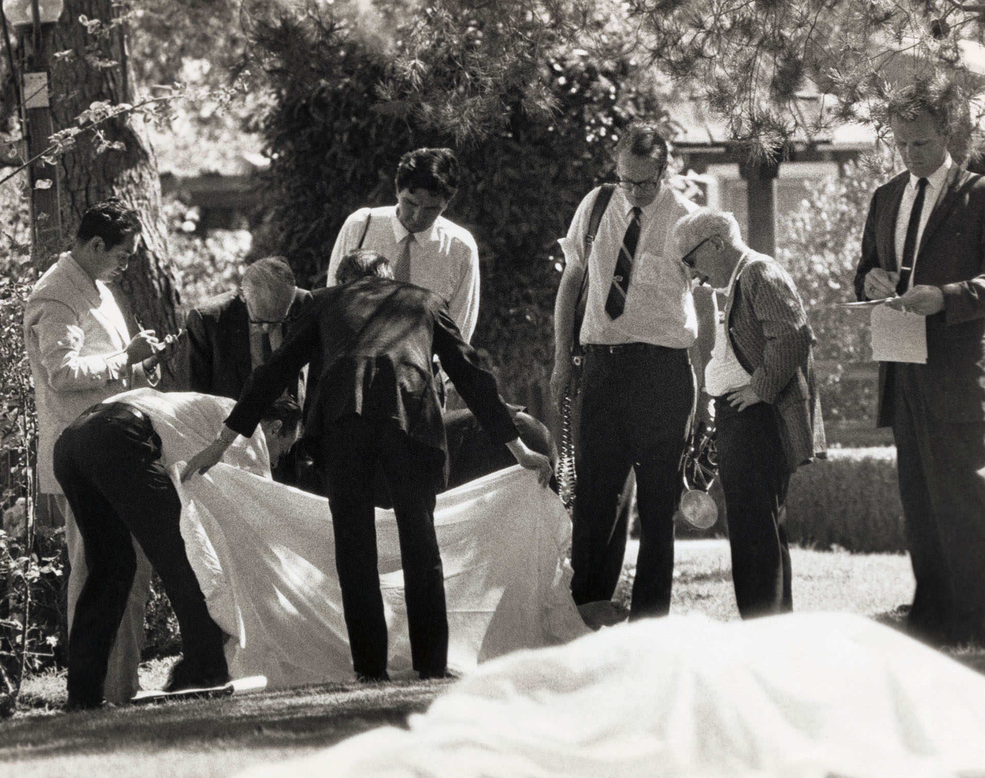 El juez de Instrucción Thomas Nogouchi toma nota mientras sus asistentes cubren uno de los cuerpos de los asesinados en la mansión de Roman Polanski y Sharon Tate