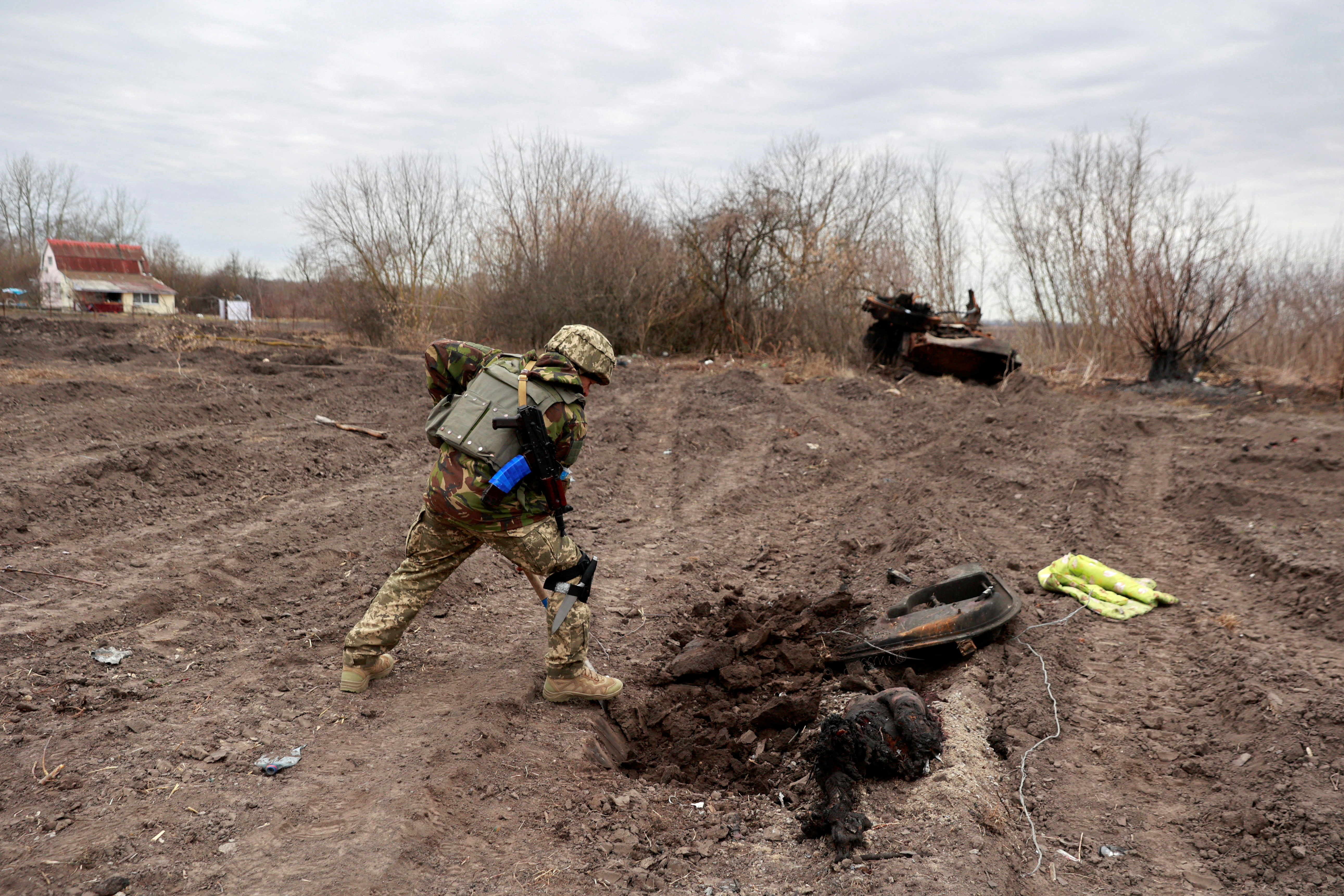 MATERIAL SENSIBLE. ESTA IMAGEN PUEDE OFENDER O MOLESTAR Un militar ucraniano entierra los restos de lo que dice que es un cadáver de un soldado ruso en el pueblo de Lukianivka que fue recientemente recuperado por las Fuerzas Armadas de Ucrania, en medio de la invasión rusa, en la región de Kyiv, Ucrania 28 de marzo de 2022. REUTERS/Serhii Nuzhnenko