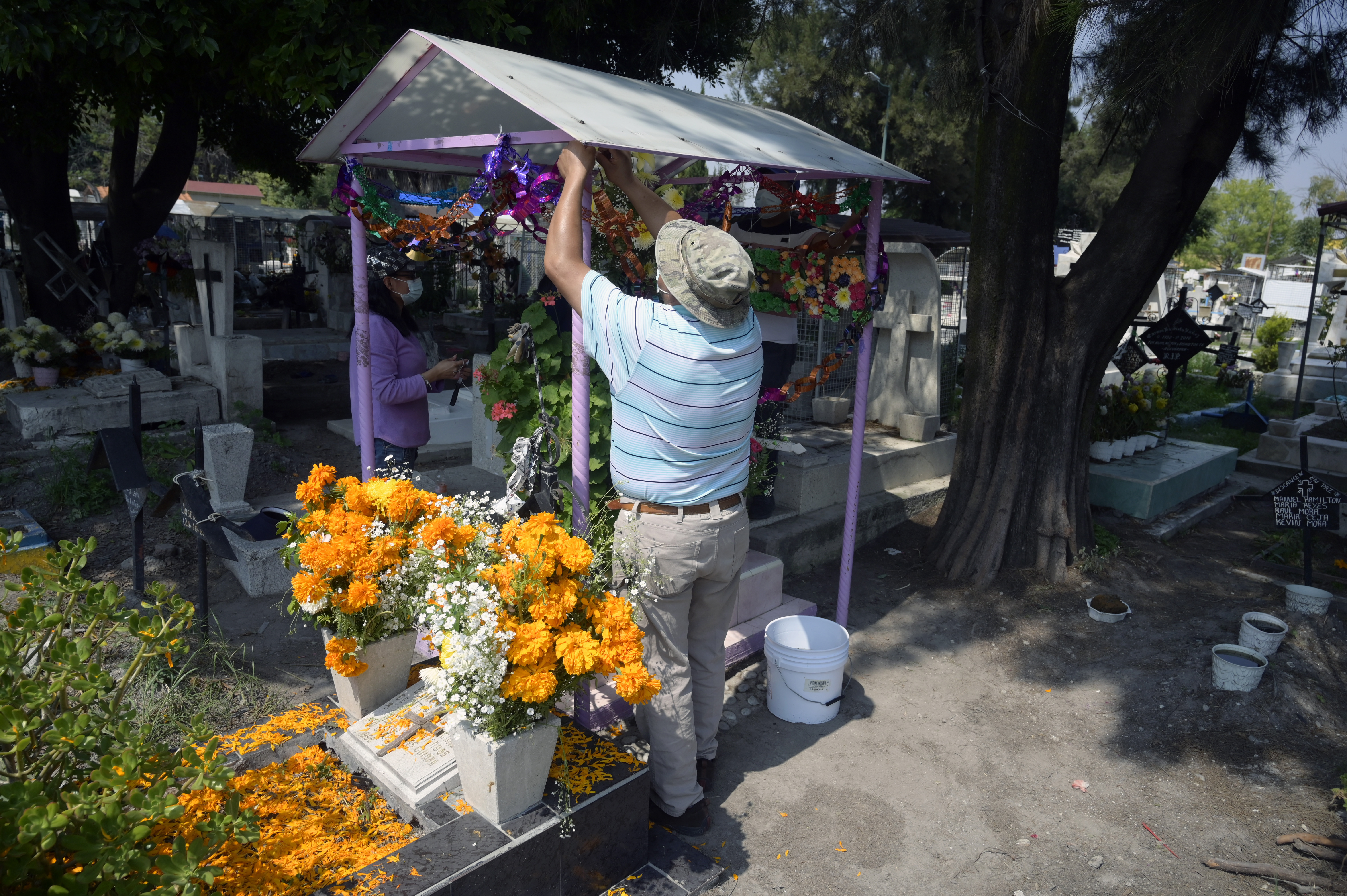 Una familia decora la tumba de su hija antes del Día de Muertos en el Panteón San José, en la Ciudad de México el 28 de octubre de 2020.