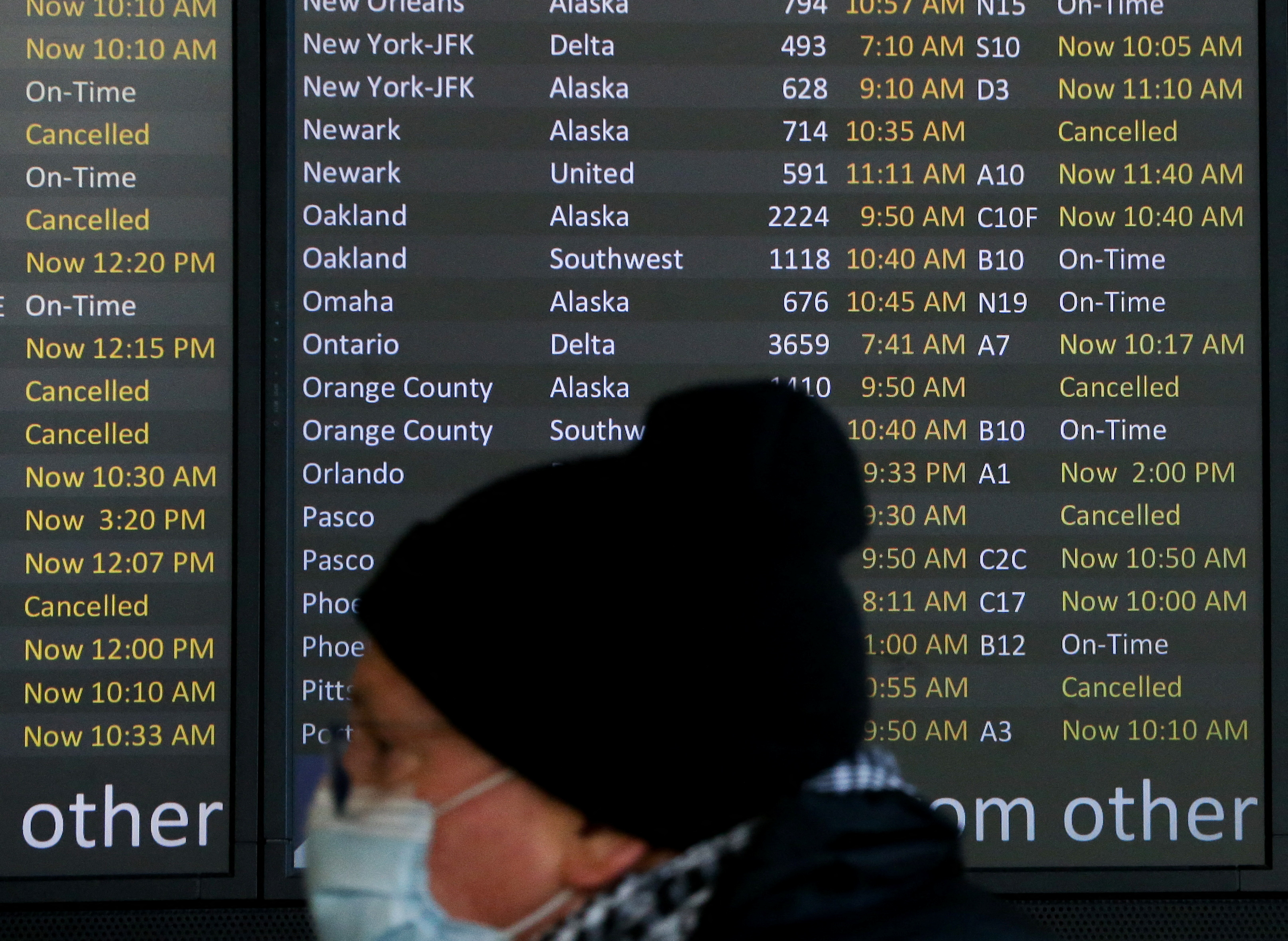 Un viajero pasa por delante de una pantalla que muestra decenas de vuelos listados como cancelados o retrasados en el Aeropuerto Internacional de Seattle-Tacoma (Sea-Tac) en Seattle, Washington, Estados Unidos (Reuters)