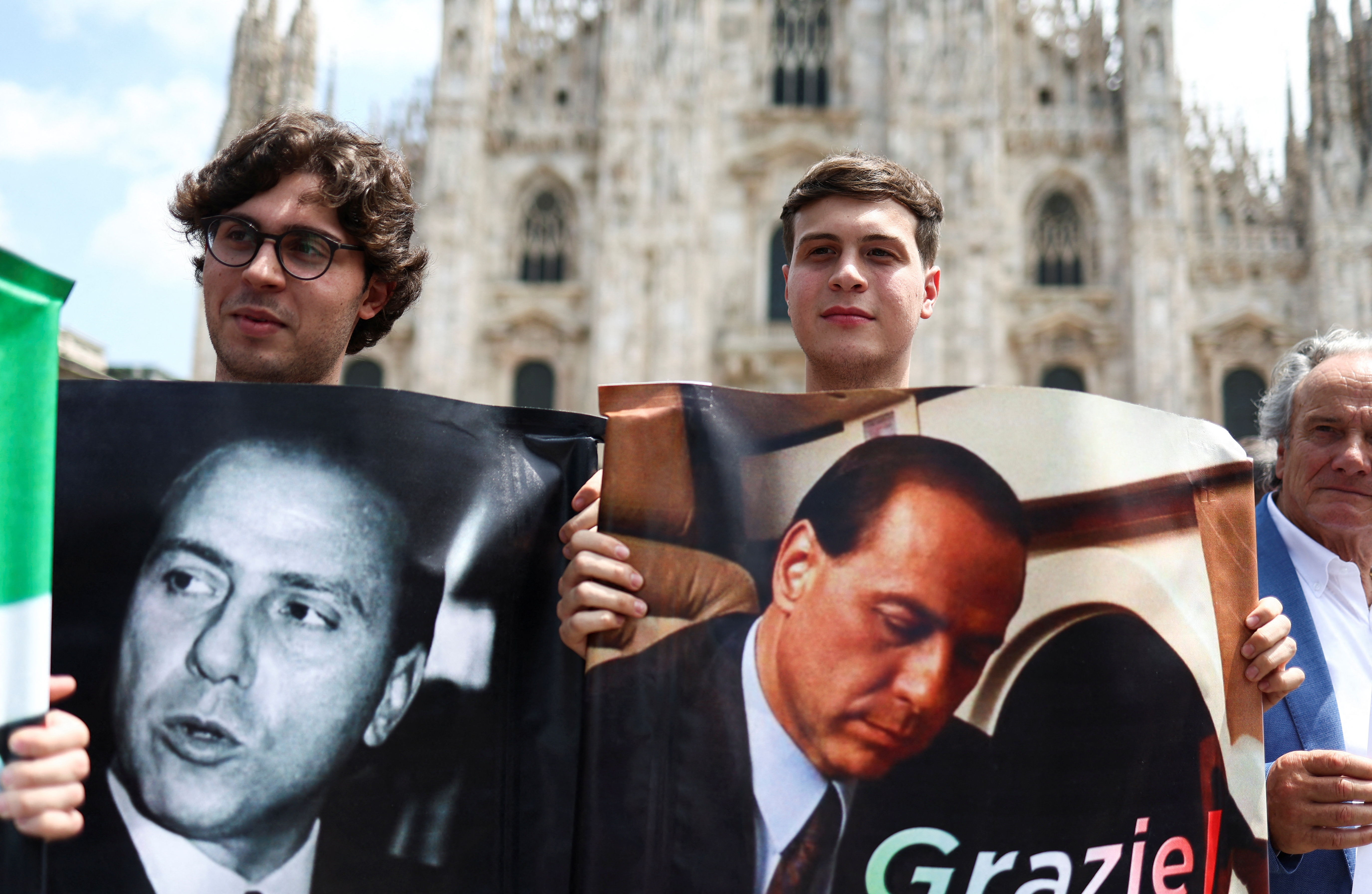 Dos jóvenes con fotos de Berlusconi frente al Duomo de Milán (REUTERS/Guglielmo Mangiapane)