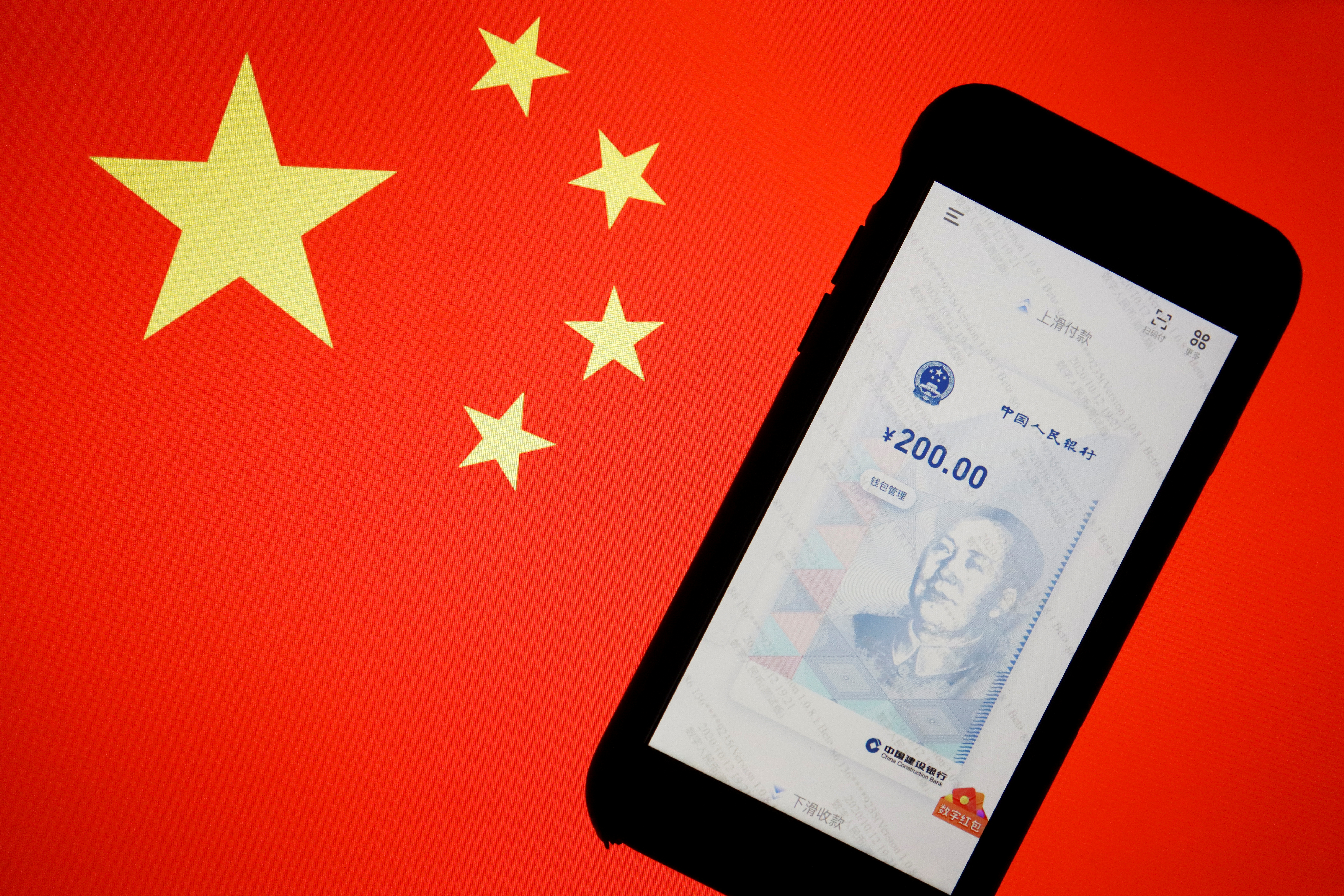 FILE PHOTO: FILE PHOTO: China's official app for digital yuan is seen on a mobile phone placed in front of an image of the Chinese flag, in this illustration picture taken October 16, 2020. REUTERS/Florence Lo/File Photo