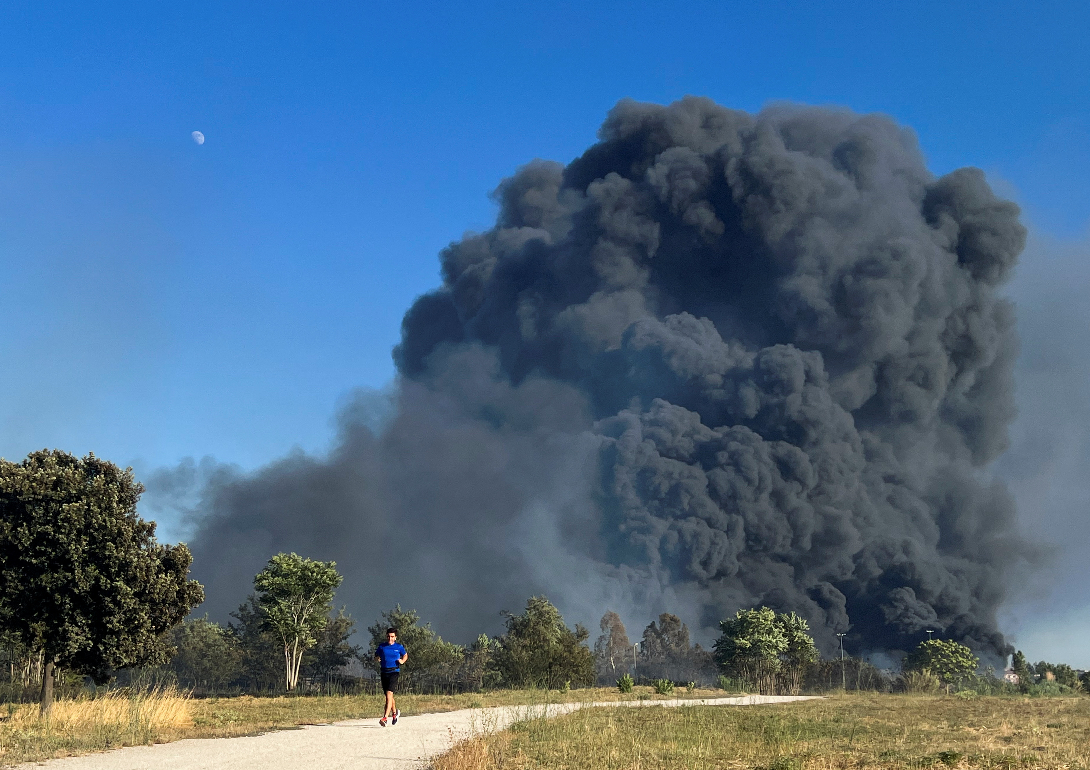 Il fumo si alza dietro un uomo nel Parco Archeologico di Centocelle il 9 luglio 2022 (REUTERS/Yara Nardi)
