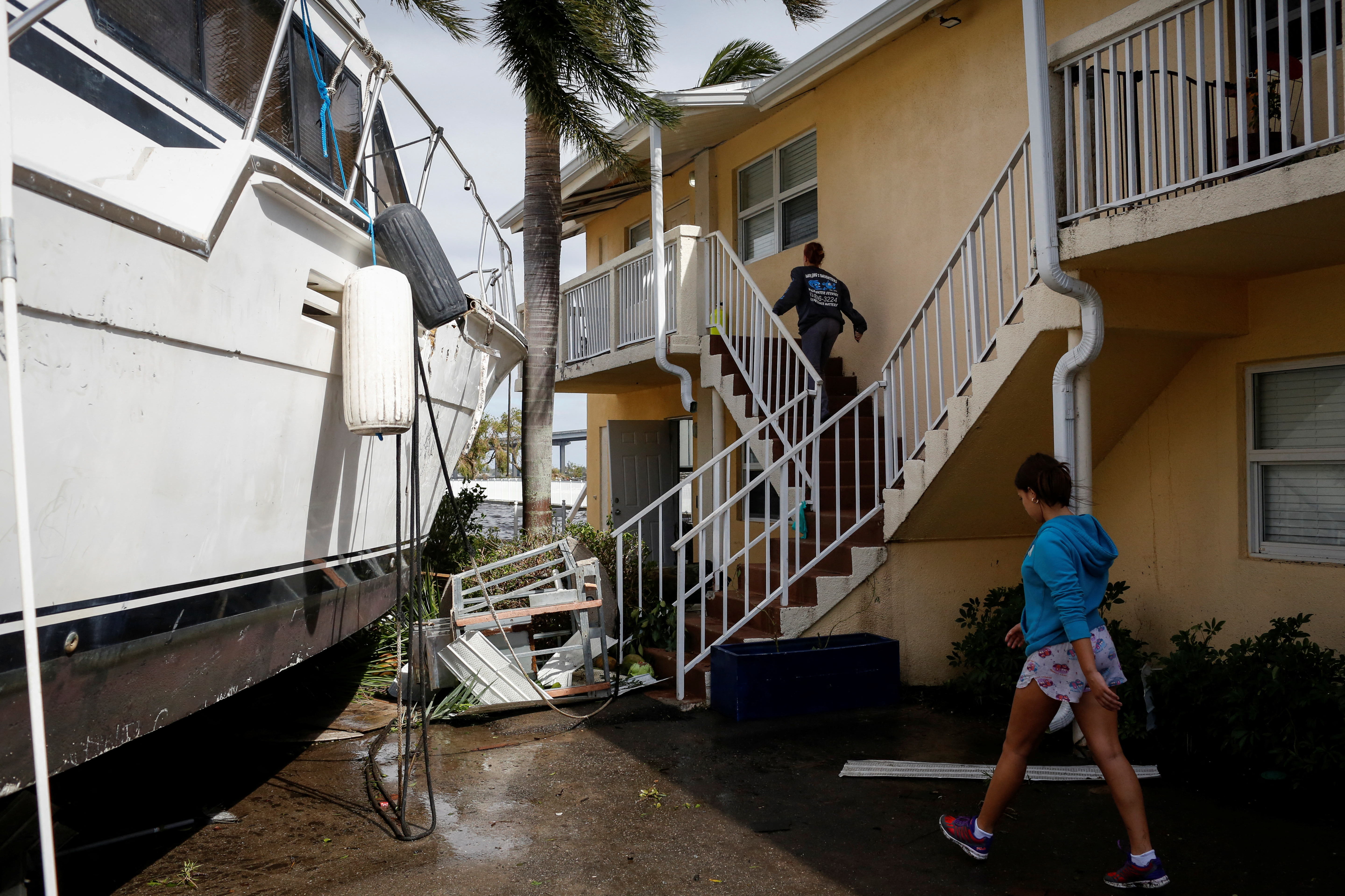 Las mujeres caminan junto a un bote dañado en medio de un condominio en el centro de la ciudad después de que el huracán Ian causara una destrucción generalizada, en Fort Myers, Florida, EE. UU., el 29 de septiembre de 2022. (REUTERS/Marco Bello)