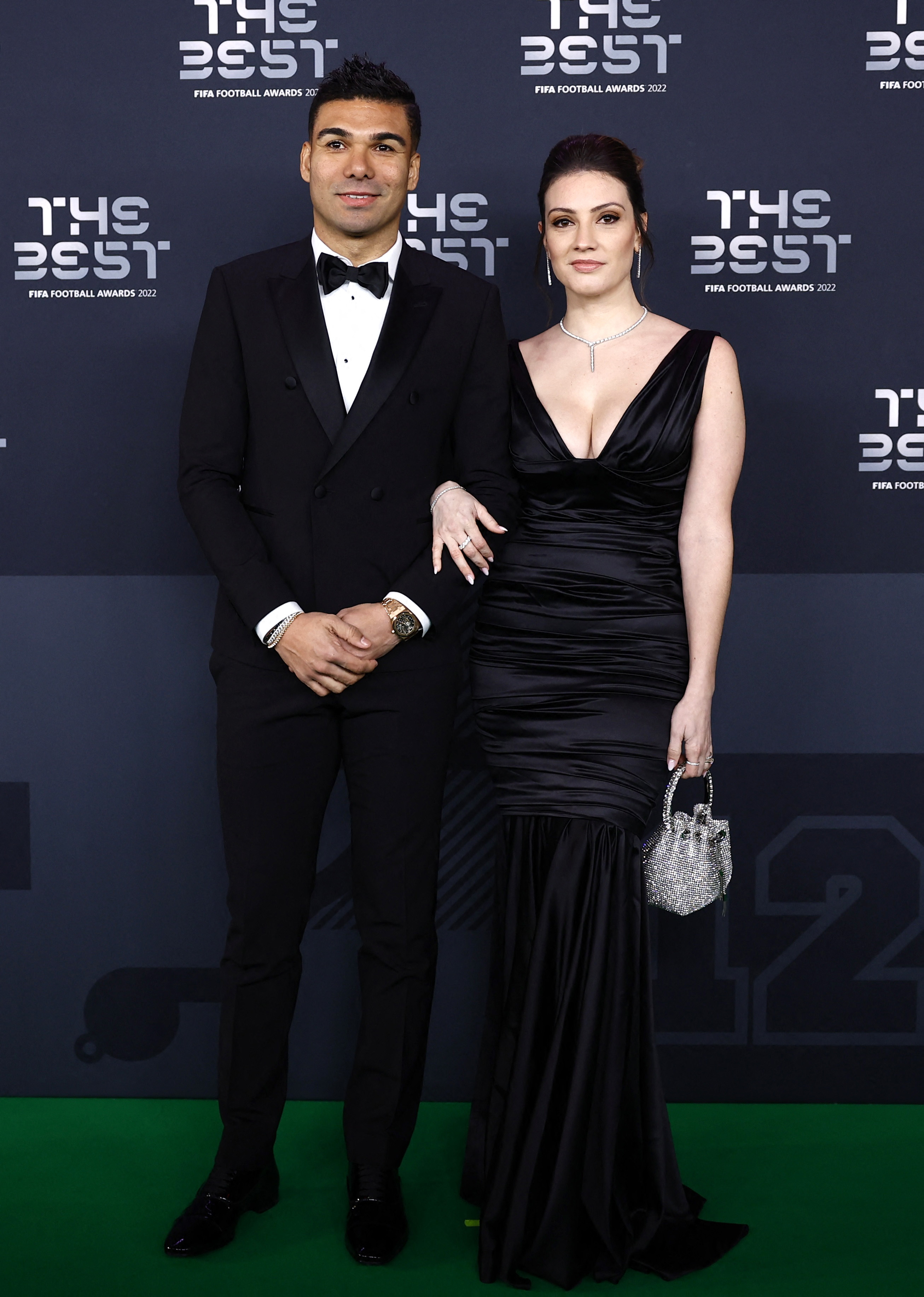 El brasileño Casemiro junto a Anna, su pareja. Ambos eligieron el color negro para sus looks. El jugador lució un traje con moño y camisa blanca y su esposa llegó a la gala con un vestido largo escotado con detalles en volado y una cartera de brillos  /REUTERS/Sarah Meyssonnier