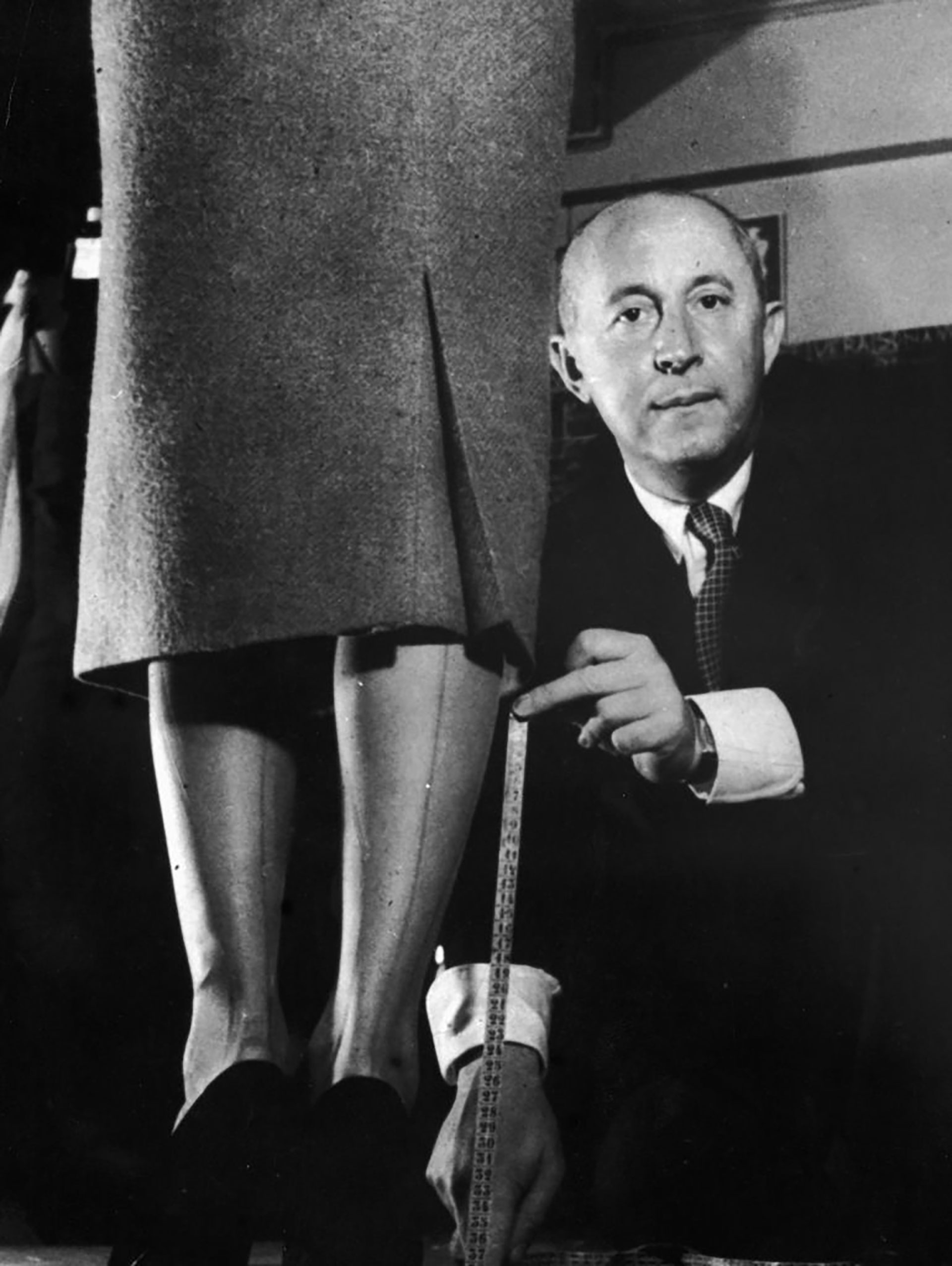 1949: el diseñador de moda francés Christian Dior demuestra con una cinta métrica y un modelo cómo revolucionó la moda bajando los dobladillos, París, Francia (Hulton Archive/Getty Images)
