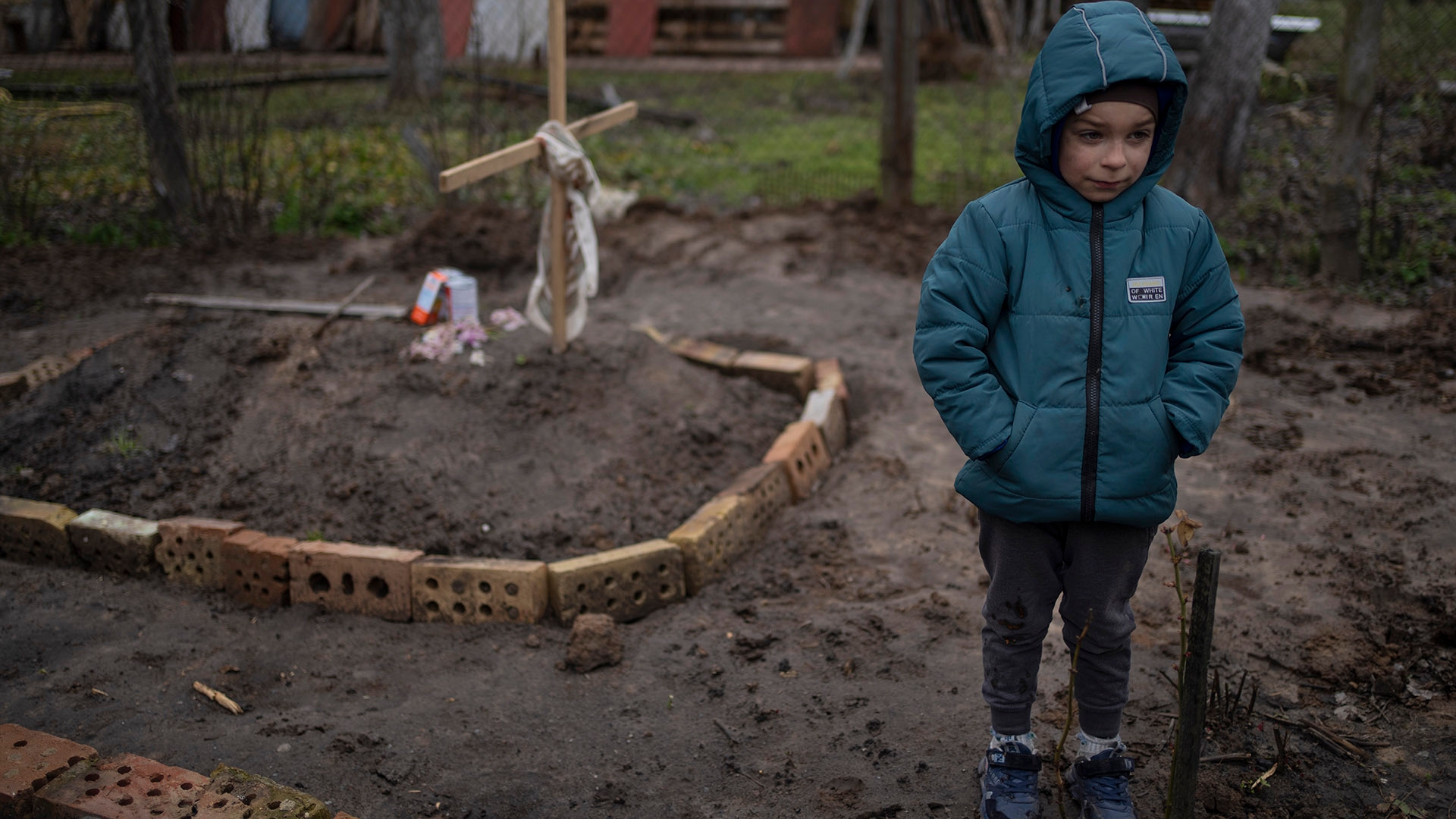 Vlad Tanyuk, de 6 años, se para junto a la tumba de su madre Ira Tanyuk, en el patio de su casa, en las afueras de Kiev, Ucrania, el lunes 4 de abril de 2022 (AP Photo/Rodrigo Abd)