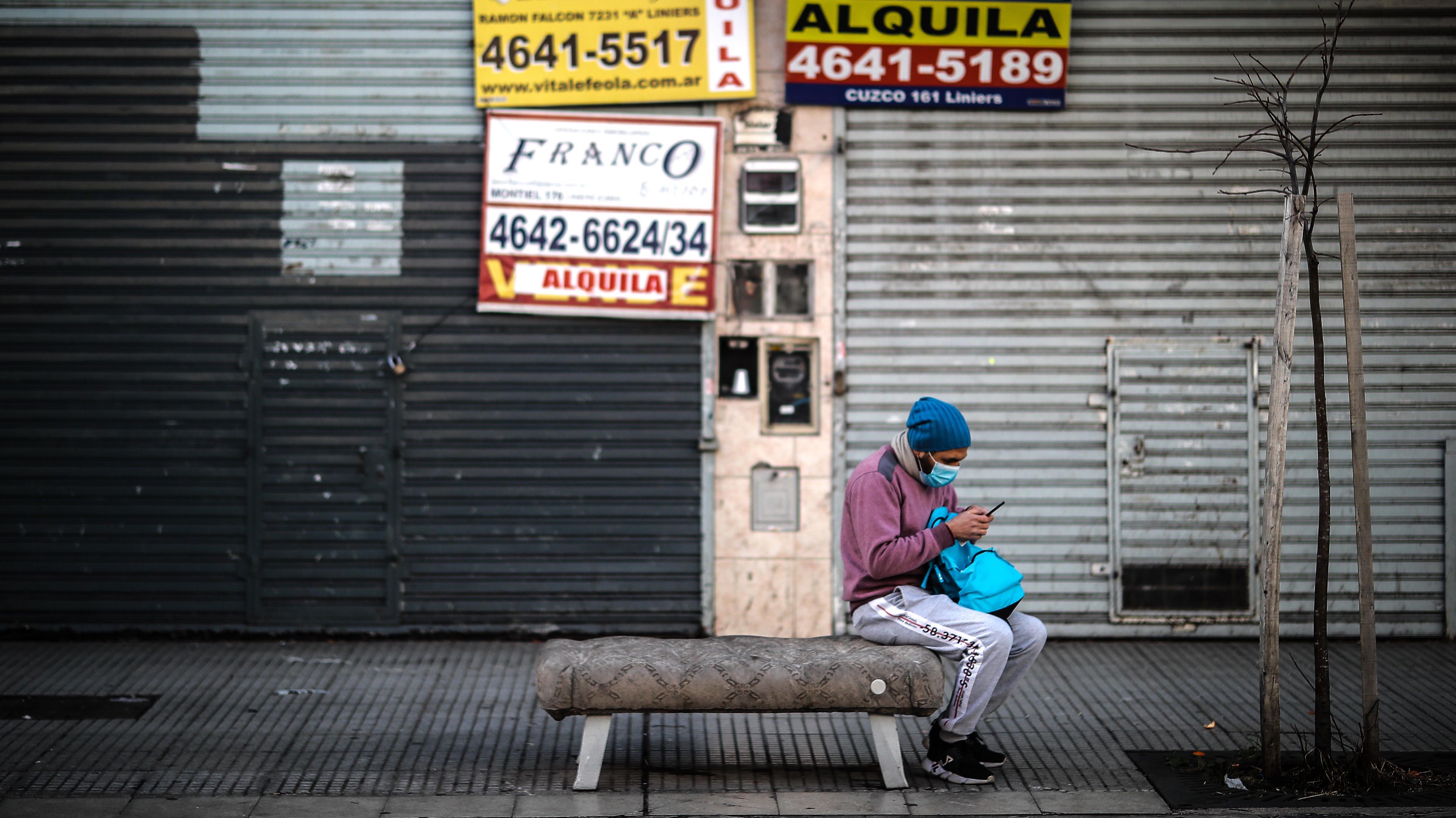 Un hombre revisa su celular frente a locales comerciales cerrados este miércoles, en Buenos Aires (Argentina). EFE/ Juan Ignacio Roncoroni