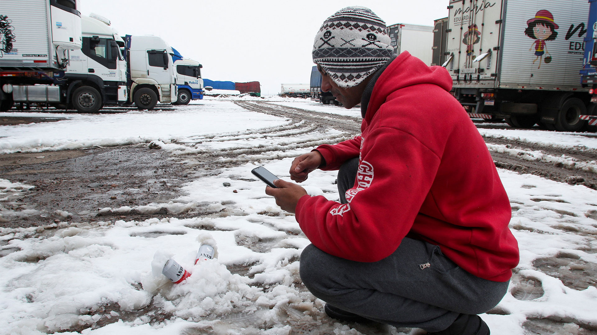 Un camionero enfría cervezas en la nieve mientras espera mejores condiciones climáticas para cruzar a Chile a través del paso internacional Cristo Redentor, en Pedriel, Mendoza