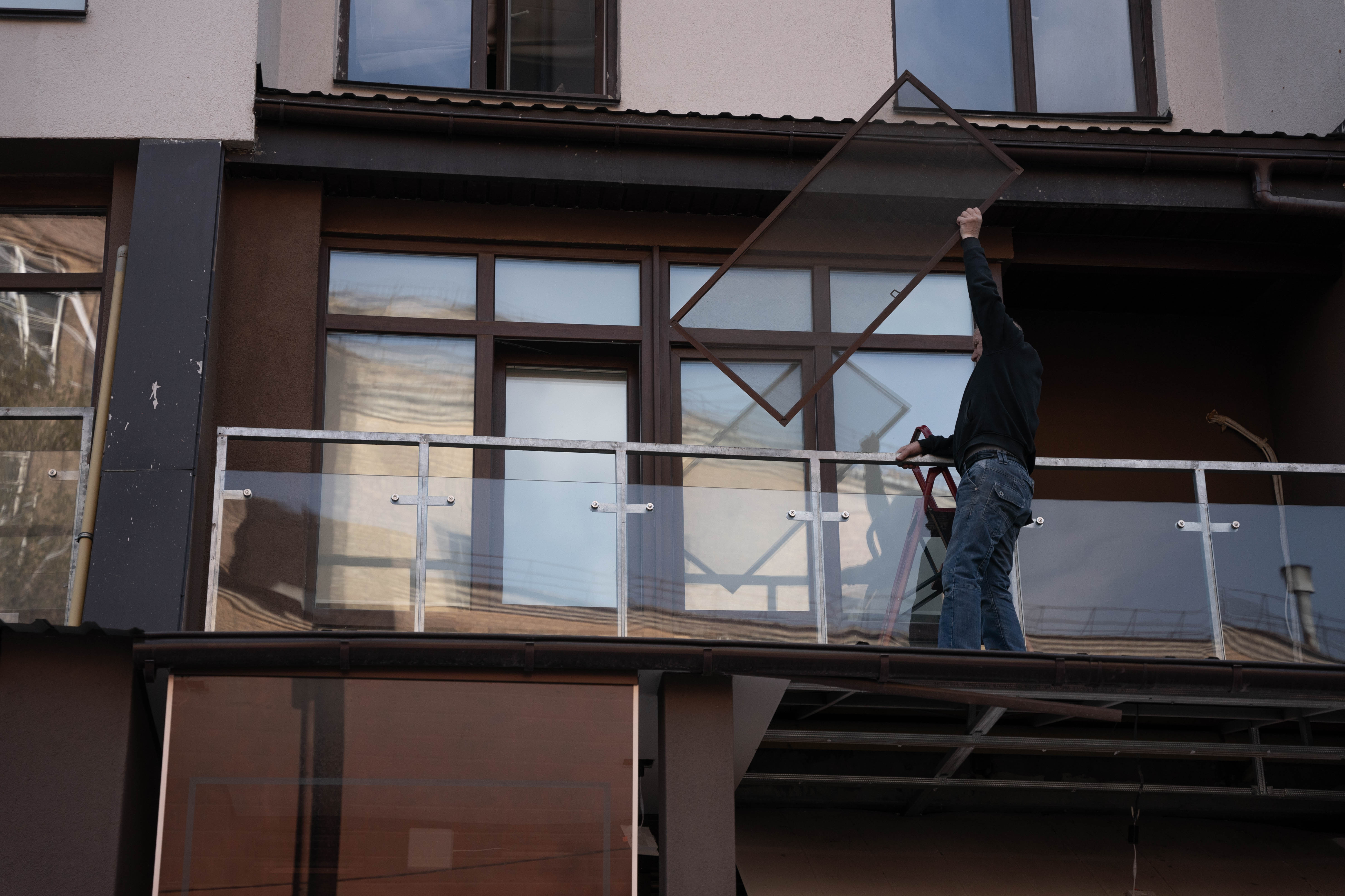 Un hombre recoge los restos de las ventanas de su departamento luego de que fuera alcanzado por un misil ruso.