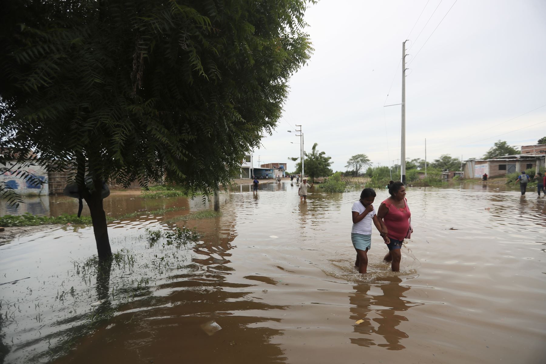 Dos personas caminan tras el desborde de los ríos por el ciclón Yaku. 