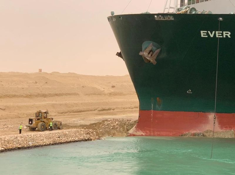 Trabajadores junto a un buque portacontenedores que fue golpeado por un fuerte viento y encalló en el Canal de Suez (Autoridad del Canal de Suez/Handout vía REUTERS)