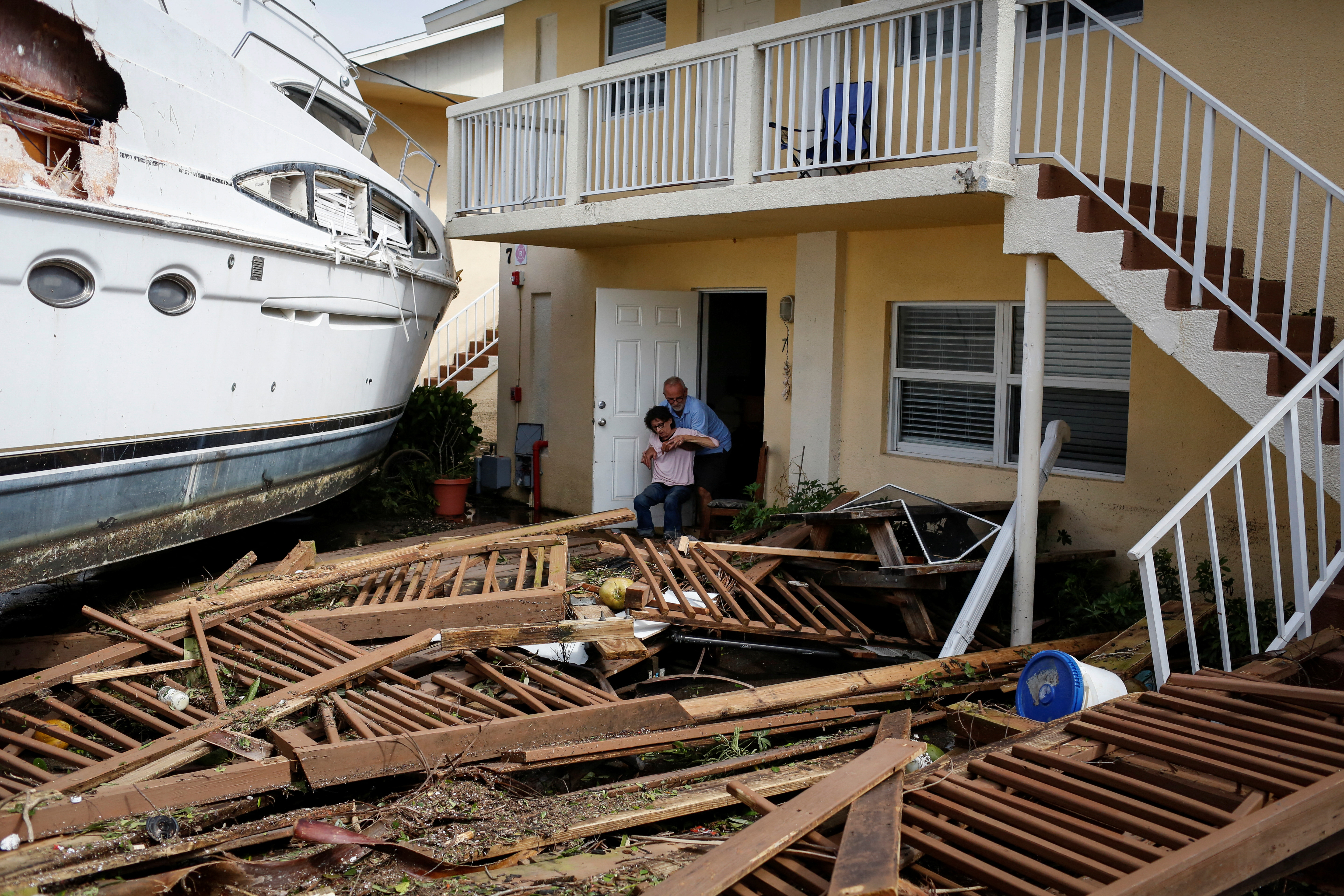 Un hombre ayuda a una mujer junto a un bote dañado en medio de un condominio en el centro de la ciudad después de que el huracán Ian causara una destrucción generalizada, en Fort Myers, Florida, el 29 de septiembre de 2022. (REUTERS/Marco Bello)