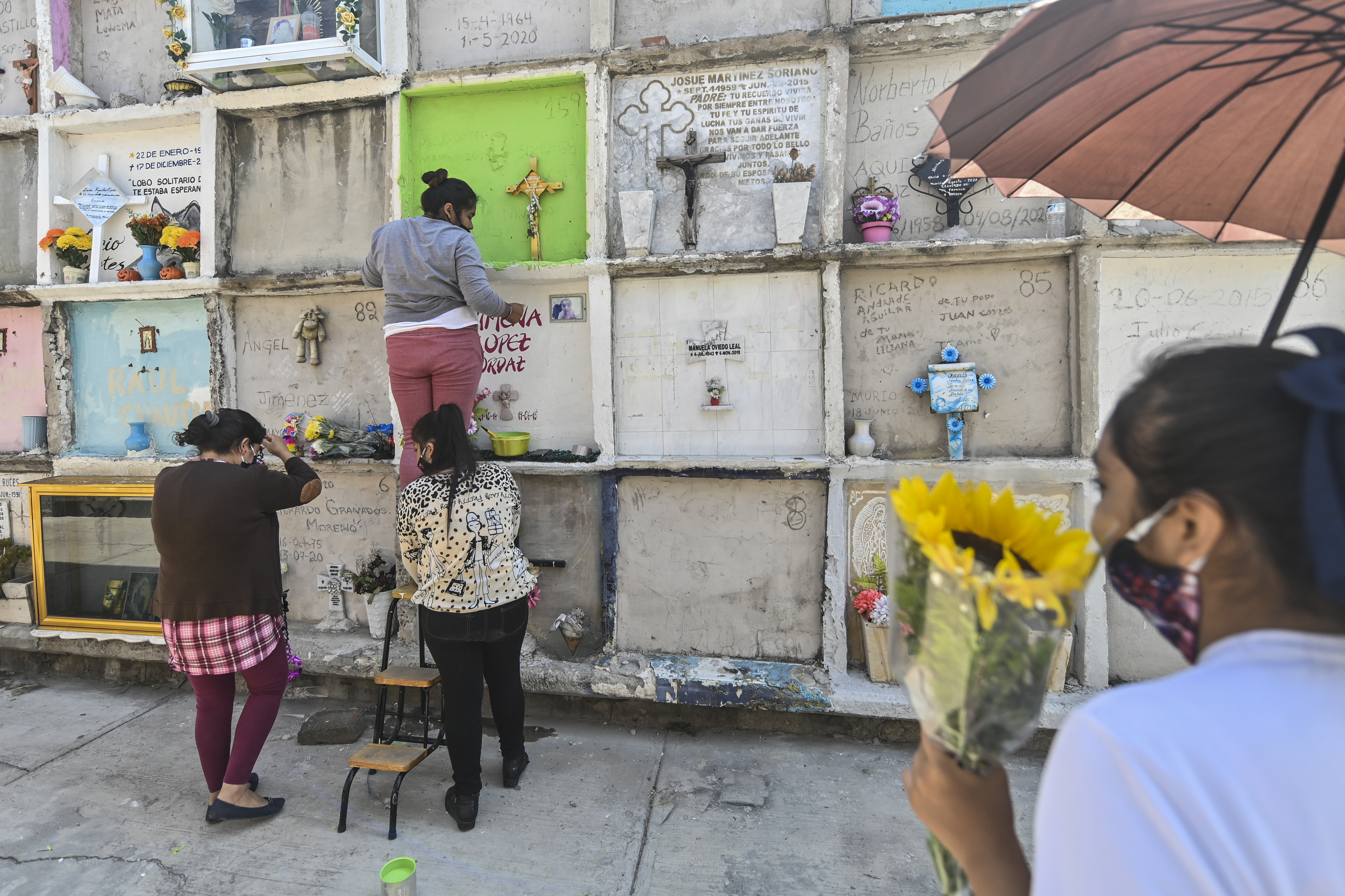 Personas decoran la tumba de un familiar antes del Día de Muertos en el panteón municipal de Nezahualcóyotl, México, el 28 de octubre de 2020, en medio de la pandemia del coronavirus COVID-19.