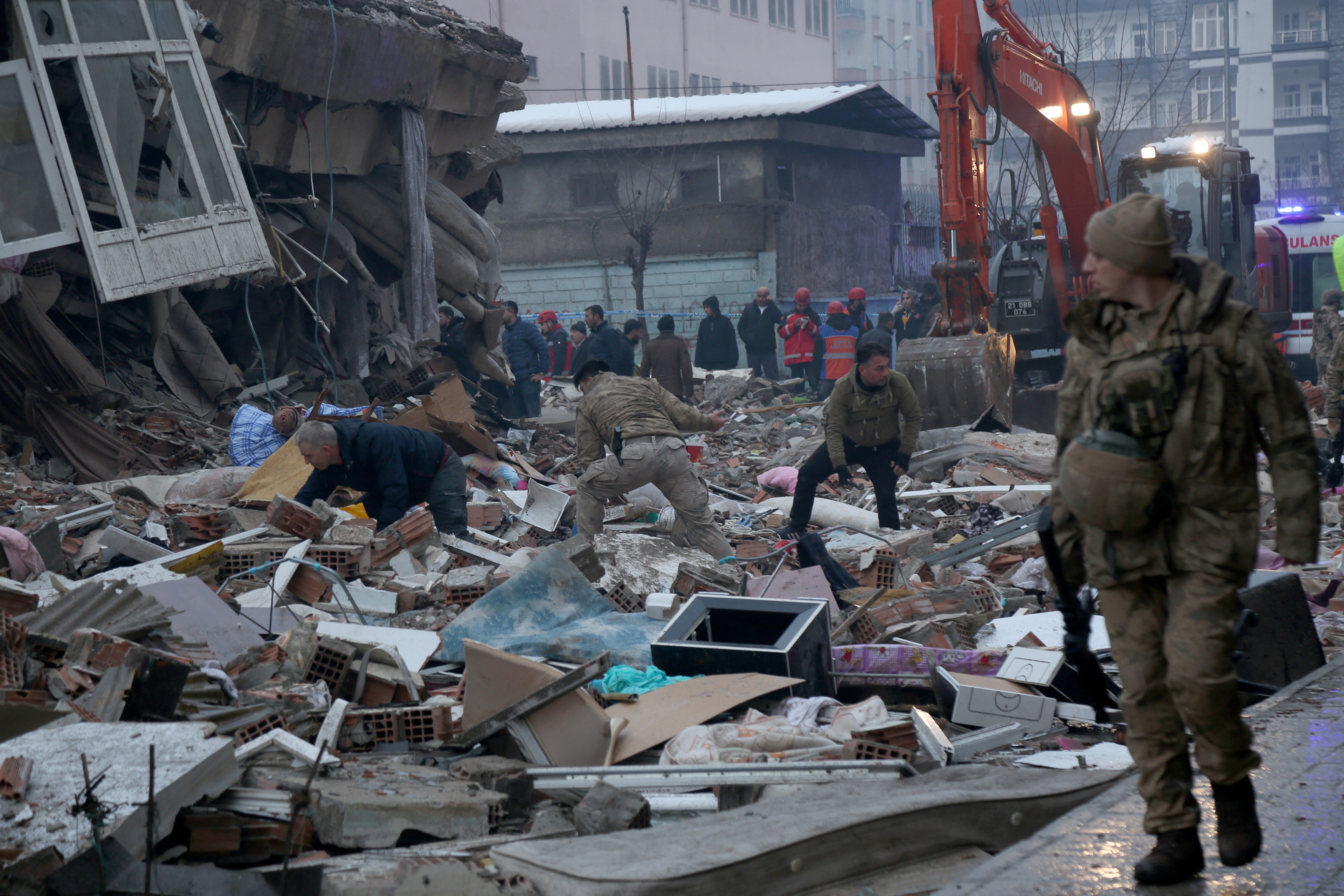 Un grupo de personas sobe escombros tratando de identificar víctimas debajo de ellos en Diyarbakir, Turquia.