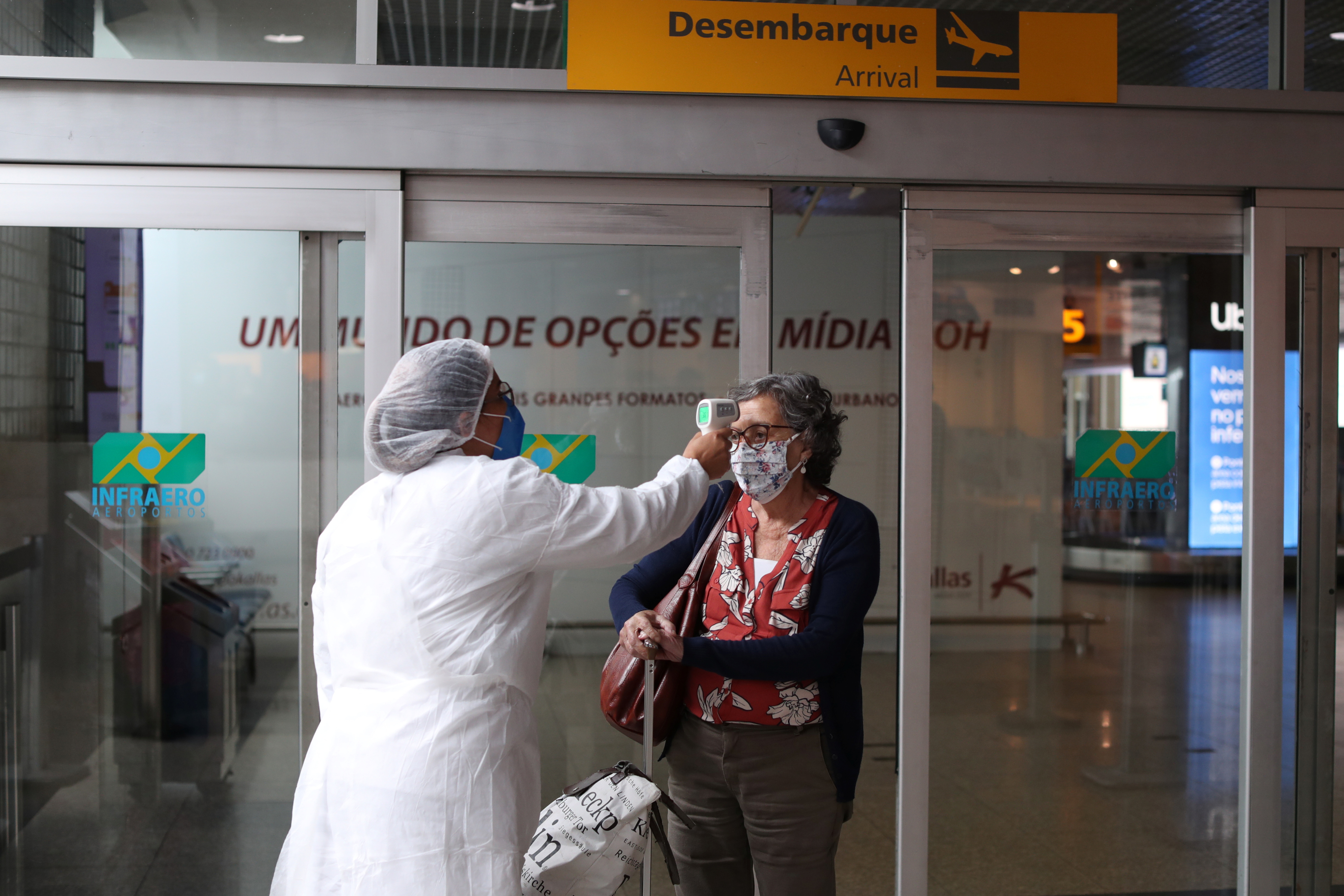Un trabajador sanitario mide la temperatura de una viajera en el Aeropuerto de Congonhas San Pablo (REUTERS/Amanda Perobelli)