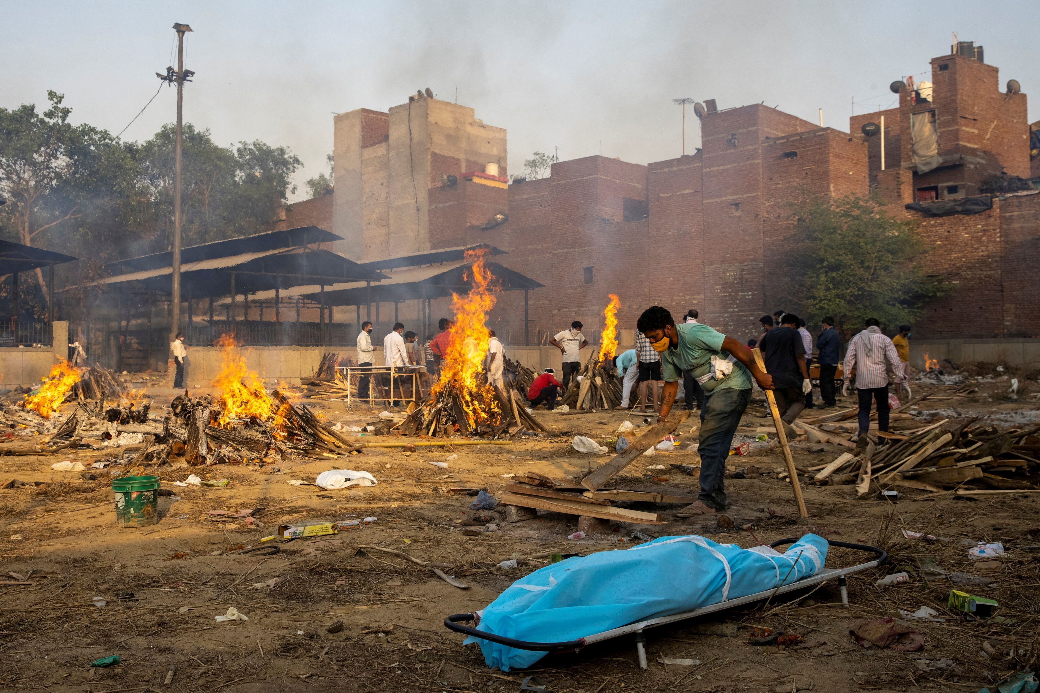Un hombre prepara una pira funeraria para incinerar el cuerpo de una persona muerta a causa del COVID-19 en Nueva Delhi (Reuters)