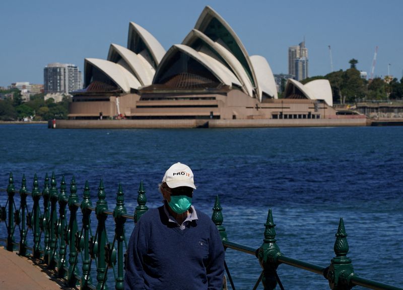 FOTO DE ARCHIVO: Una persona con mascarilla camina por el paseo marítimo del puerto frente a la Ópera de Sídney durante un cierre para frenar la propagación de la enfermedad del coronavirus (COVID-19) en Sídney, Australia, el 6 de octubre de 2021. REUTERS/Loren Elliott