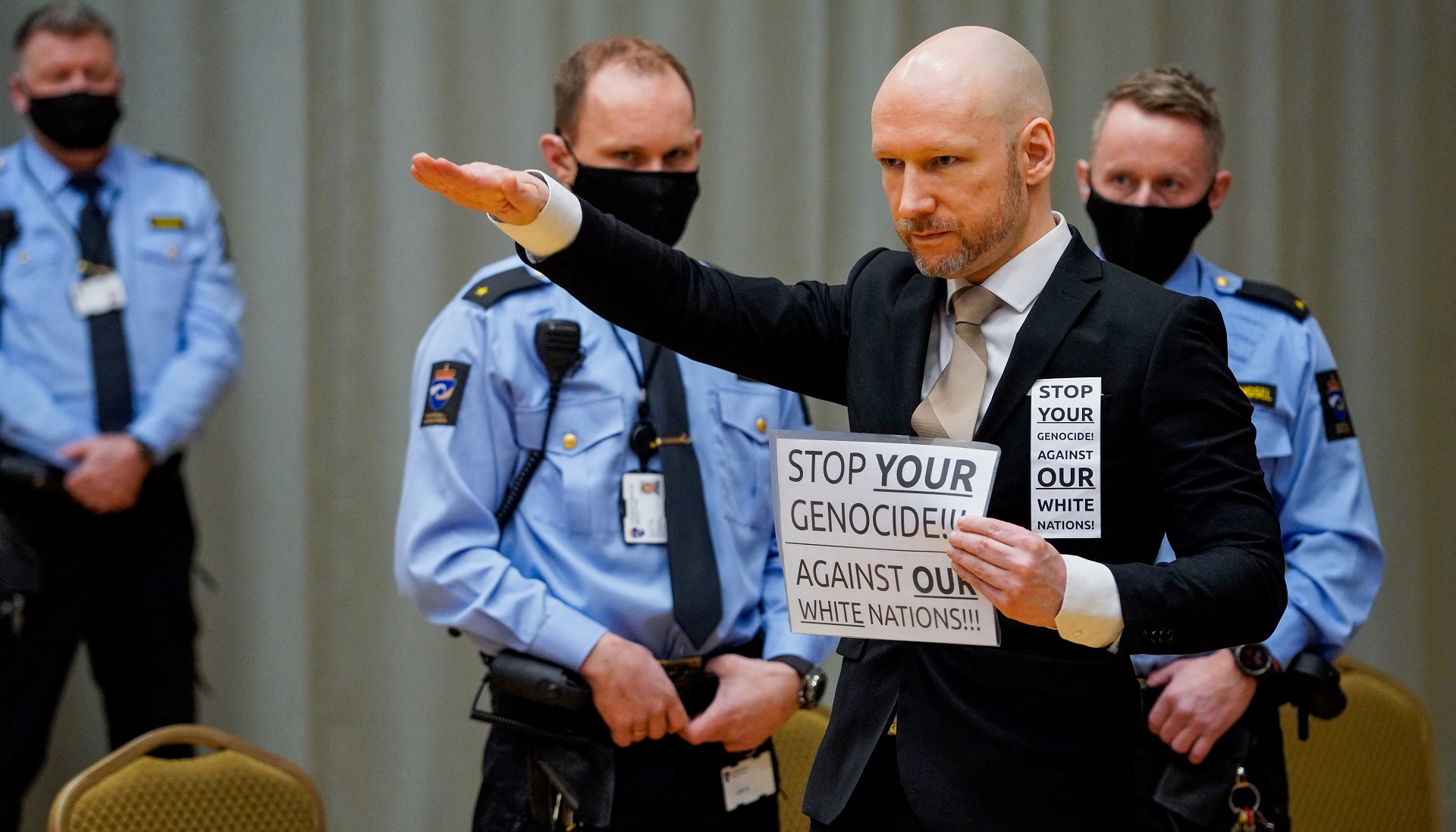 Anders Behring Breivik y el saludo nazi ante los jueces: "Detengan su genocidio contra nuestras naciones blancas", dice el cartel que exhibió (AFP)