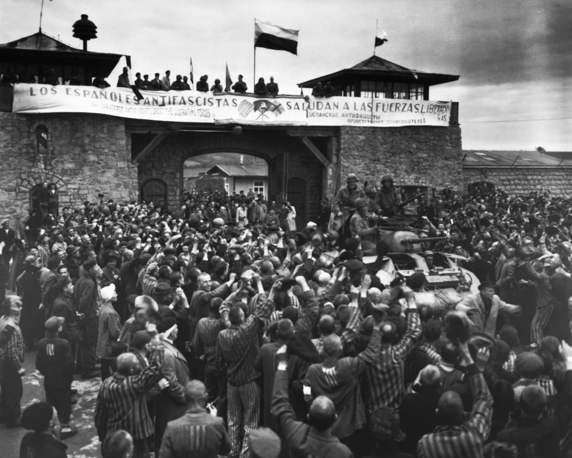 Los prisioneros liberados en el campo de concentración de Mauthausen, cerca de Linz, Austria, dan una calurosa bienvenida a los soldados de caballería de la 11.ª División Blindada. La pancarta antifascista en la pared fue hecha por prisioneros republicanos españoles (Corbis vía Getty Images)
