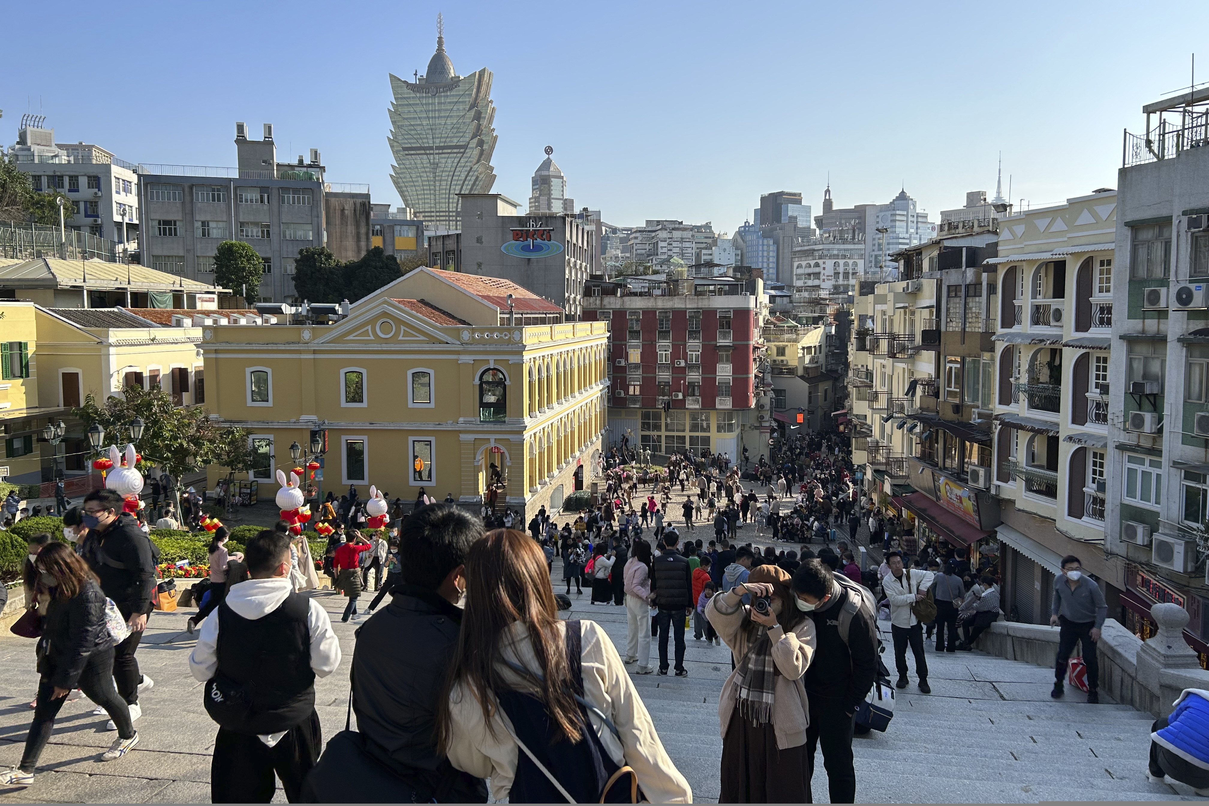 Viajeros chinos recorren las escalinatas que llevan a las ruinas de la iglesia de San Pablo, el miércoles 18 de enero de 2022, en Macao. (AP Foto/Kanis Leung)