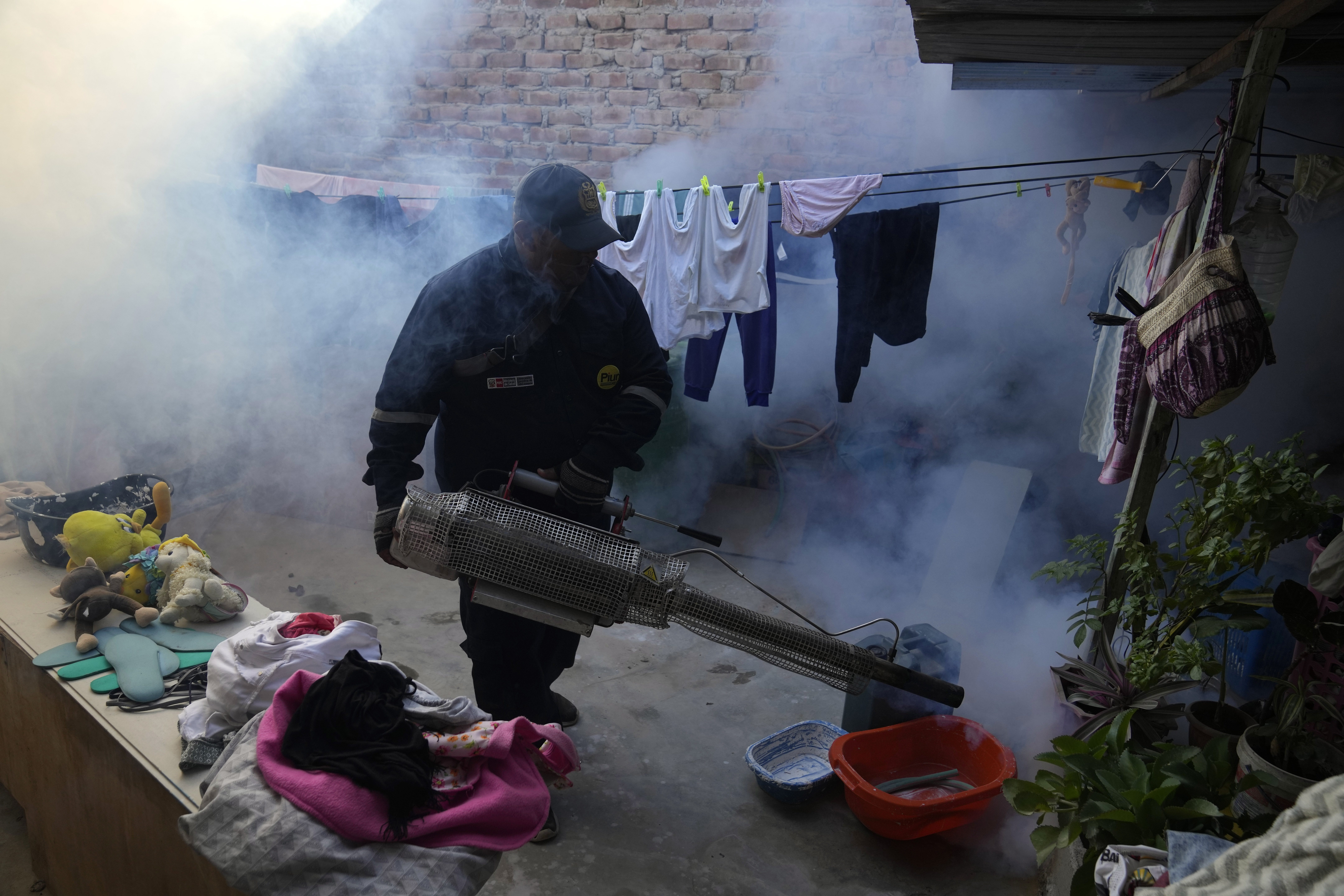 Un trabajador de salud fumiga contra los mosquitos para ayudar a mitigar la propagación del dengue en una casa en el barrio marginal La Primavera en Piura, Perú, el sábado 3 de junio de 2023. (AP Foto/Martín Mejía)