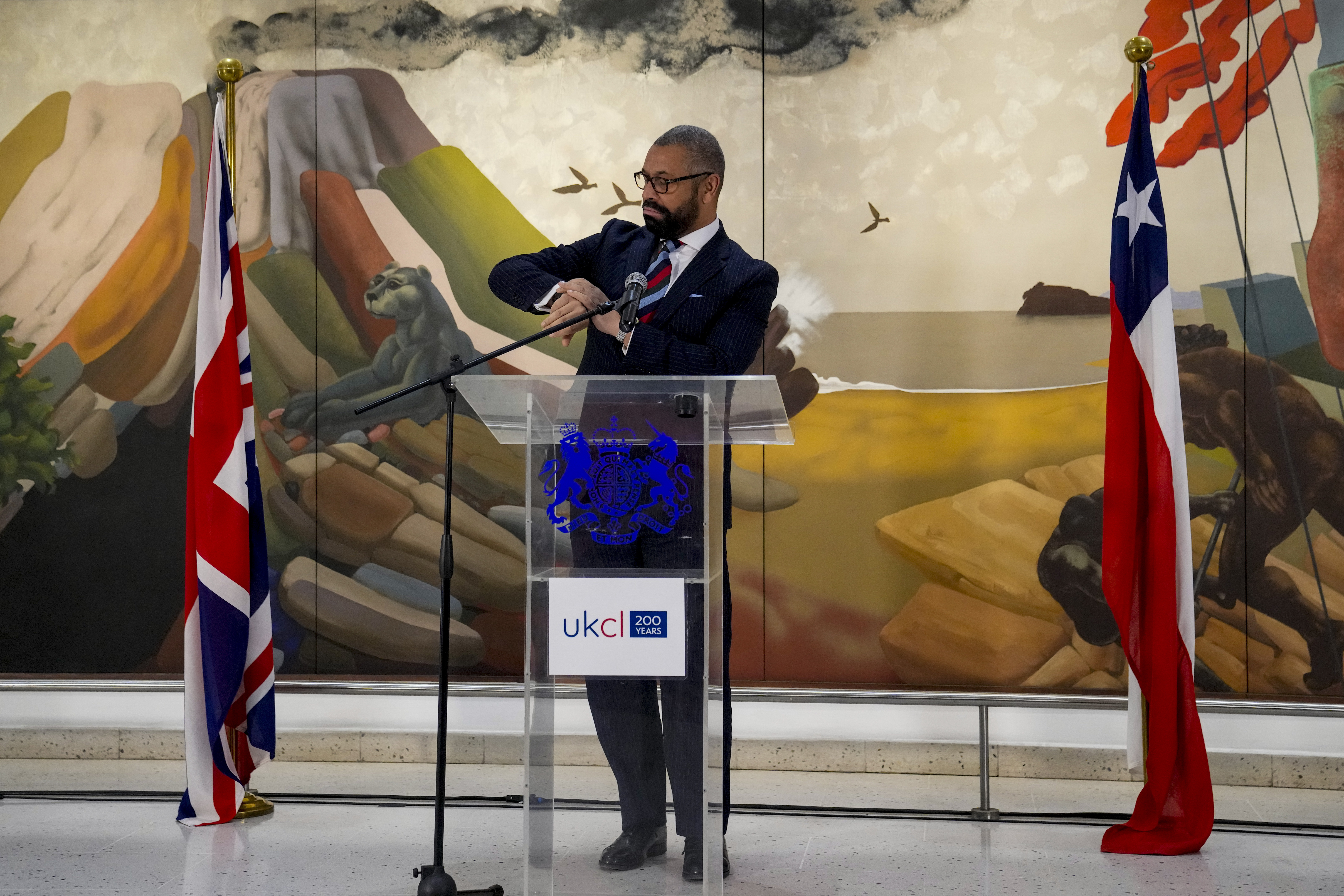 James Cleverly mira su reloj mientras habla en una conferencia sobre la relación del Reino Unido con América Latina en Santiago de Chile (Foto AP/Esteban Félix)