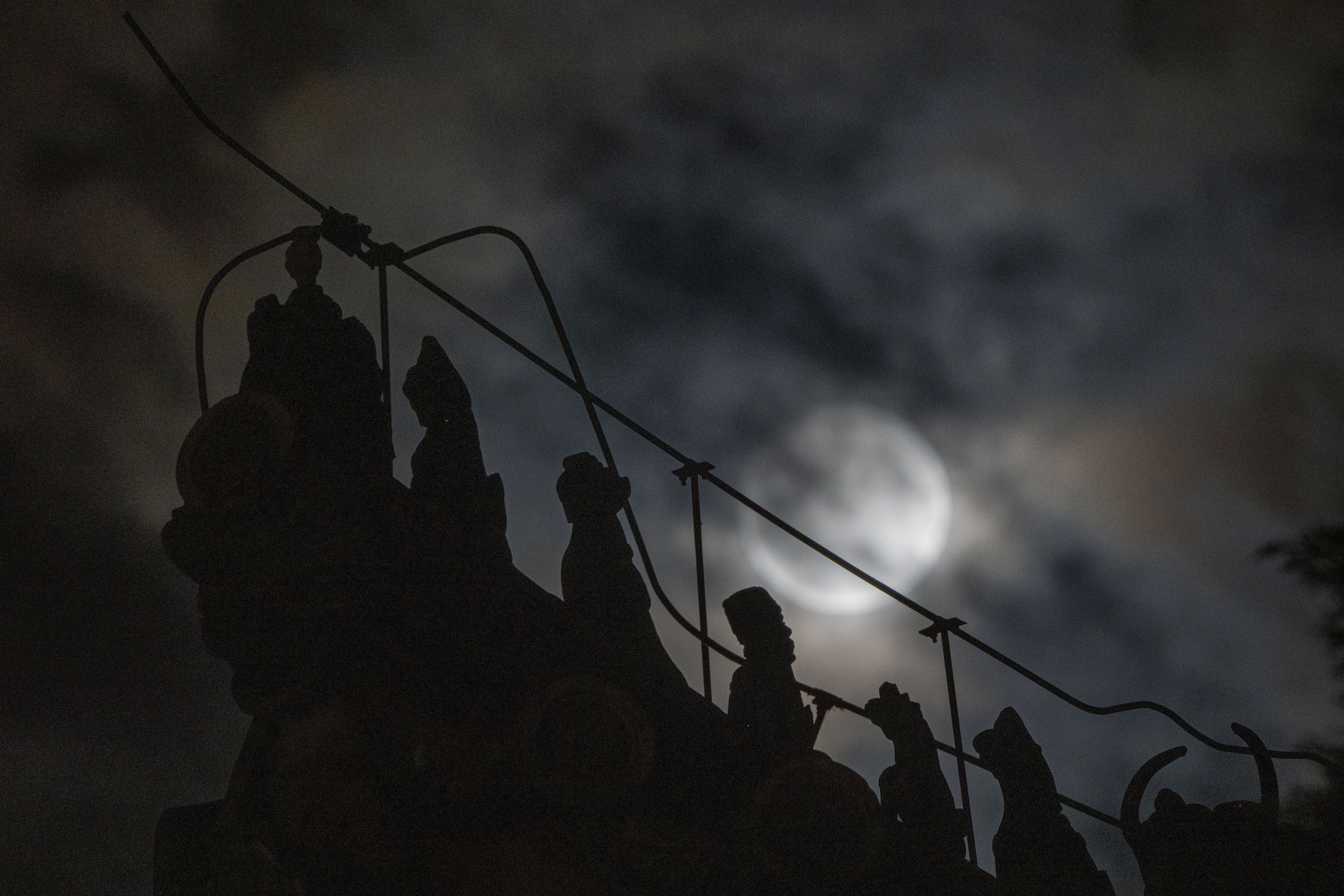 Las decoraciones del techo que representan bestias sagradas míticas se recortan cerca de un eclipse lunar penumbral parcialmente bloqueado por las nubes durante las primeras horas del sábado (Foto AP/Ng Han Guan)