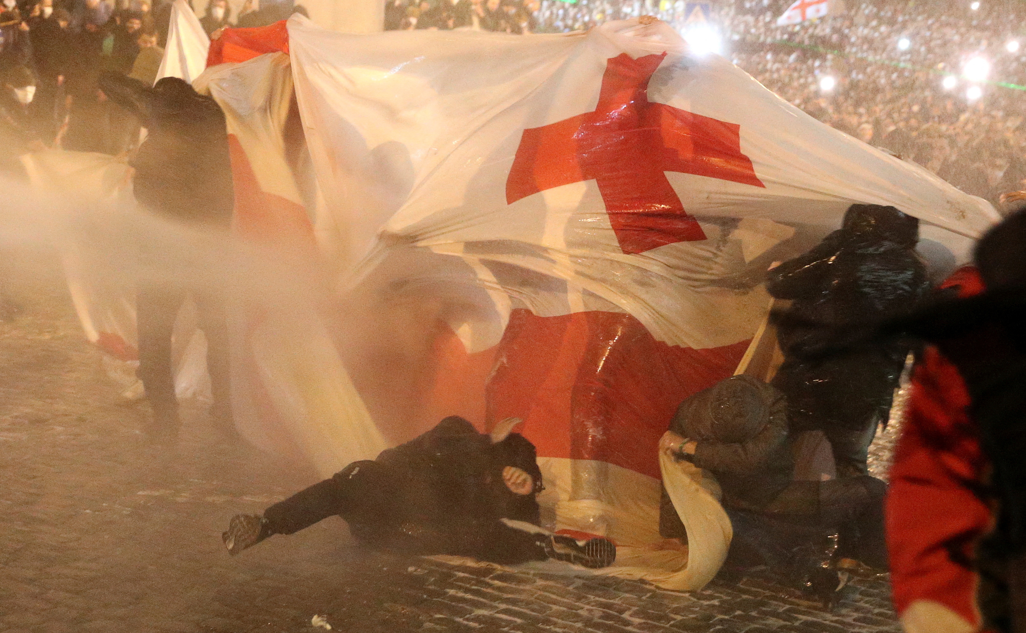 La policía reprime a los manifestantes que llevan una bandera georgiana y se oponen a la ley de "agente extranjero". (REUTERS/Irakli Gedenidze)     