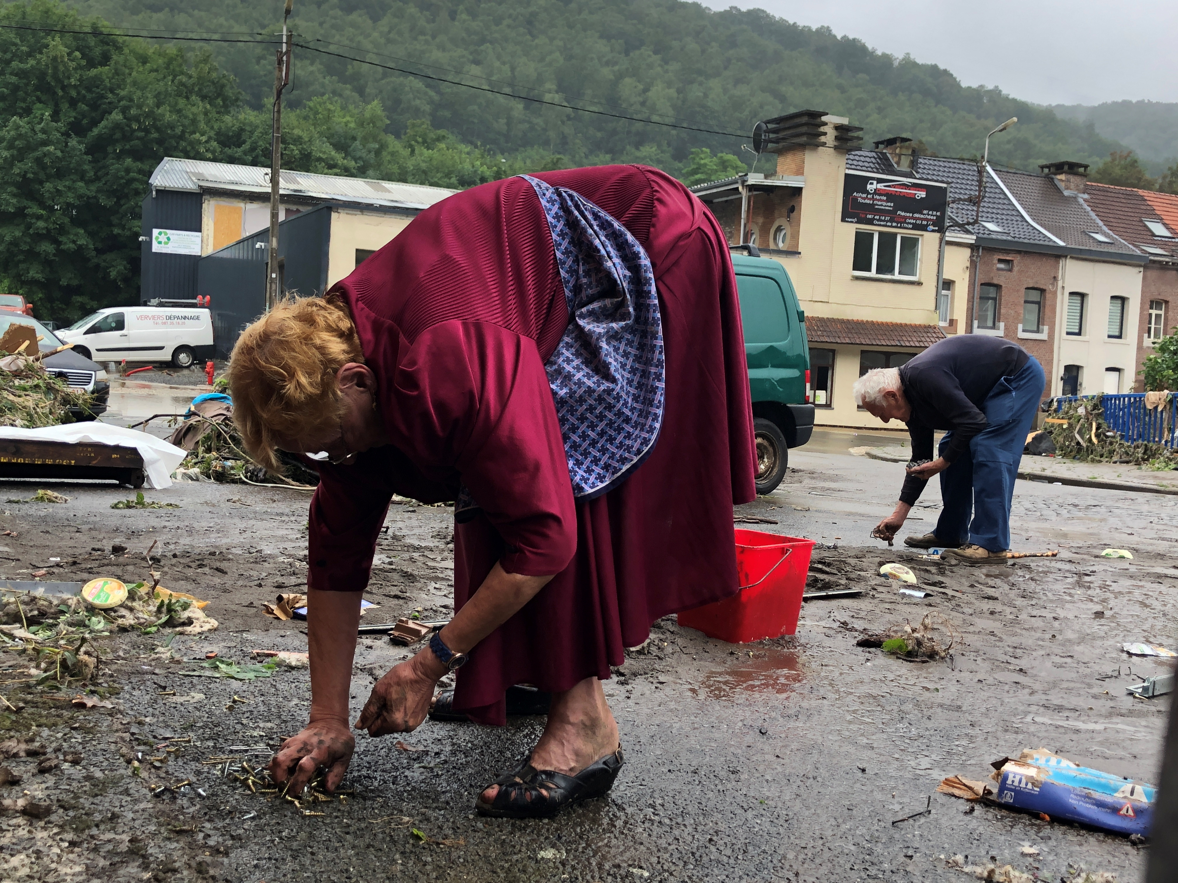 Personas limpian una calle afectada por las inundaciones en Pepinster, Bélgica