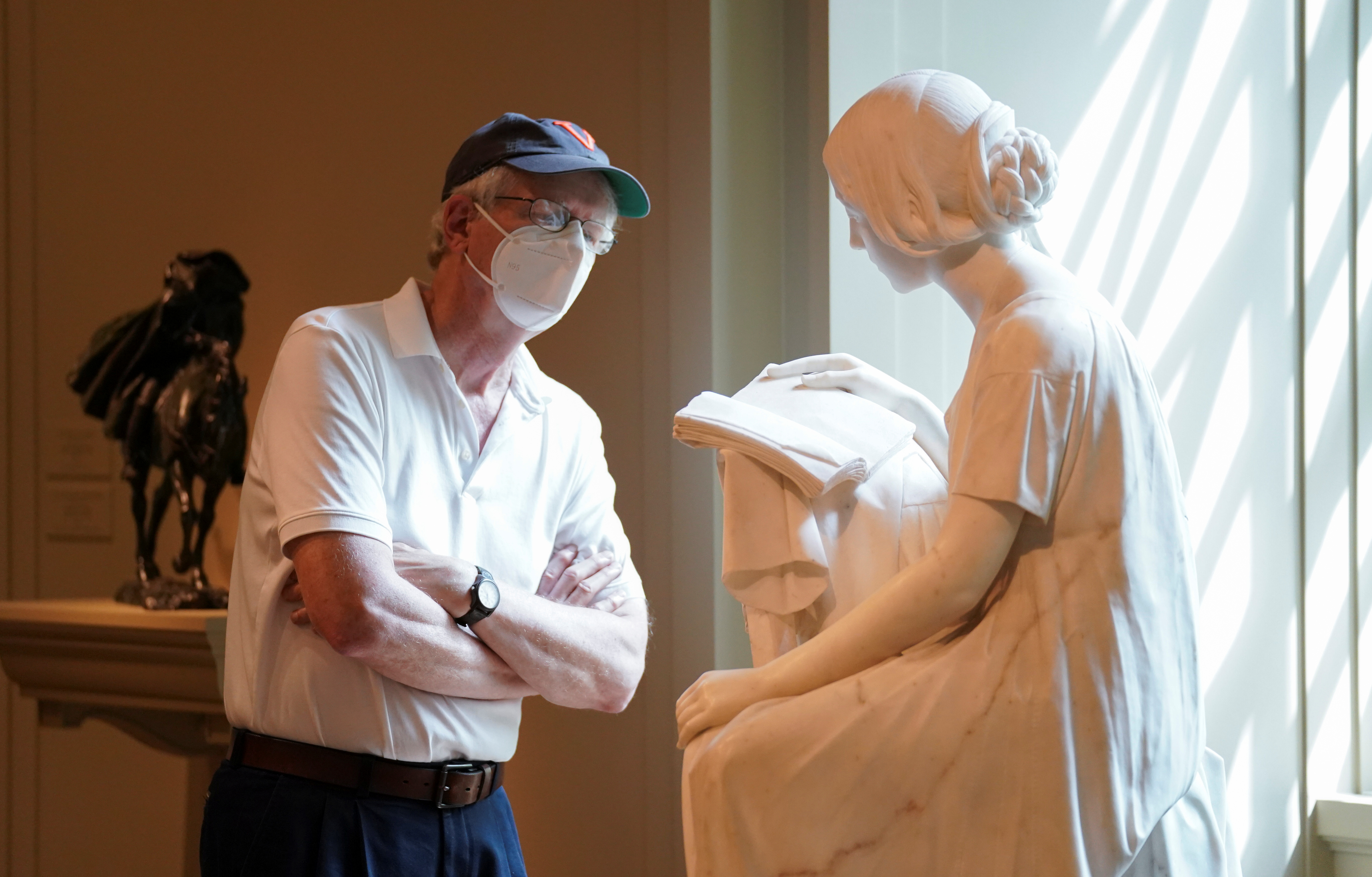 Un visitante observa la escultura "La niña lectora" de Pietro Magni, en la National Gallery of Art de Washington, que reabrió con todos los recaudos en julio luego de meses de cierre por la pandemia. (REUTERS/Kevin Lamarque)