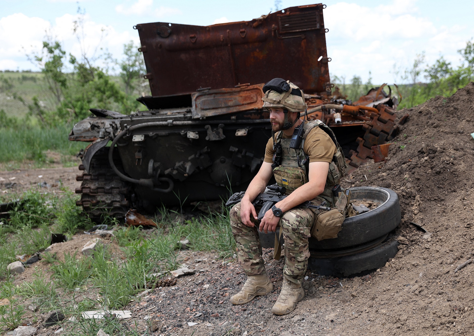 Un militar ucraniano se sienta junto a un tanque ruso destruido en una posición rusa abandonada cerca de la aldea de Bilogorivka, no lejos de Lisychansk, región de Lugansk, el 17 de junio de 2022. (Foto de Anatolii STEPANOV / AFP)