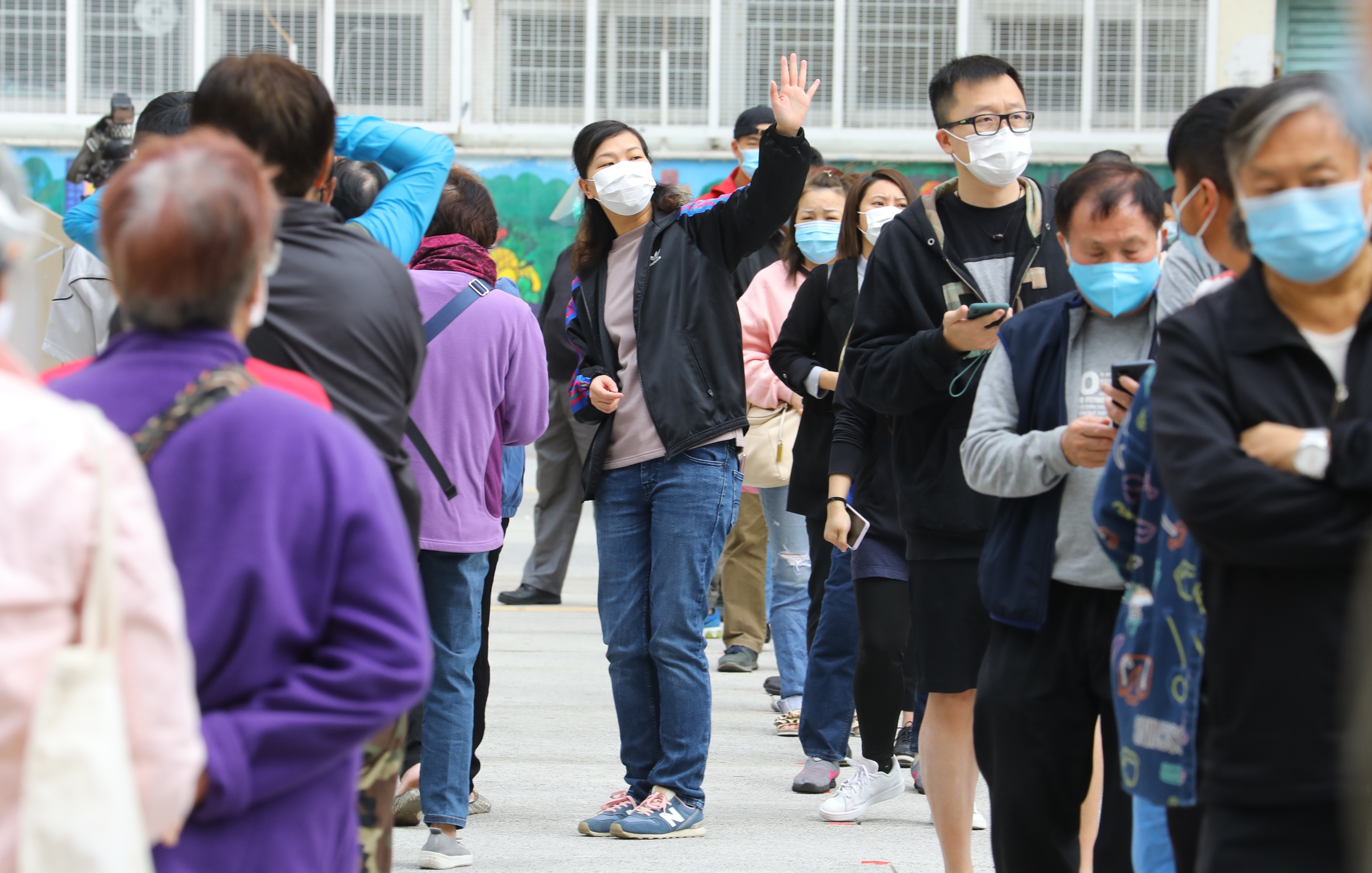 Un grupo de residentes de uno de los edificios en los que se ha localizado un último brote de la COVID-19 en Hong Kong hace turno para someterse a una prueba de coronavirus