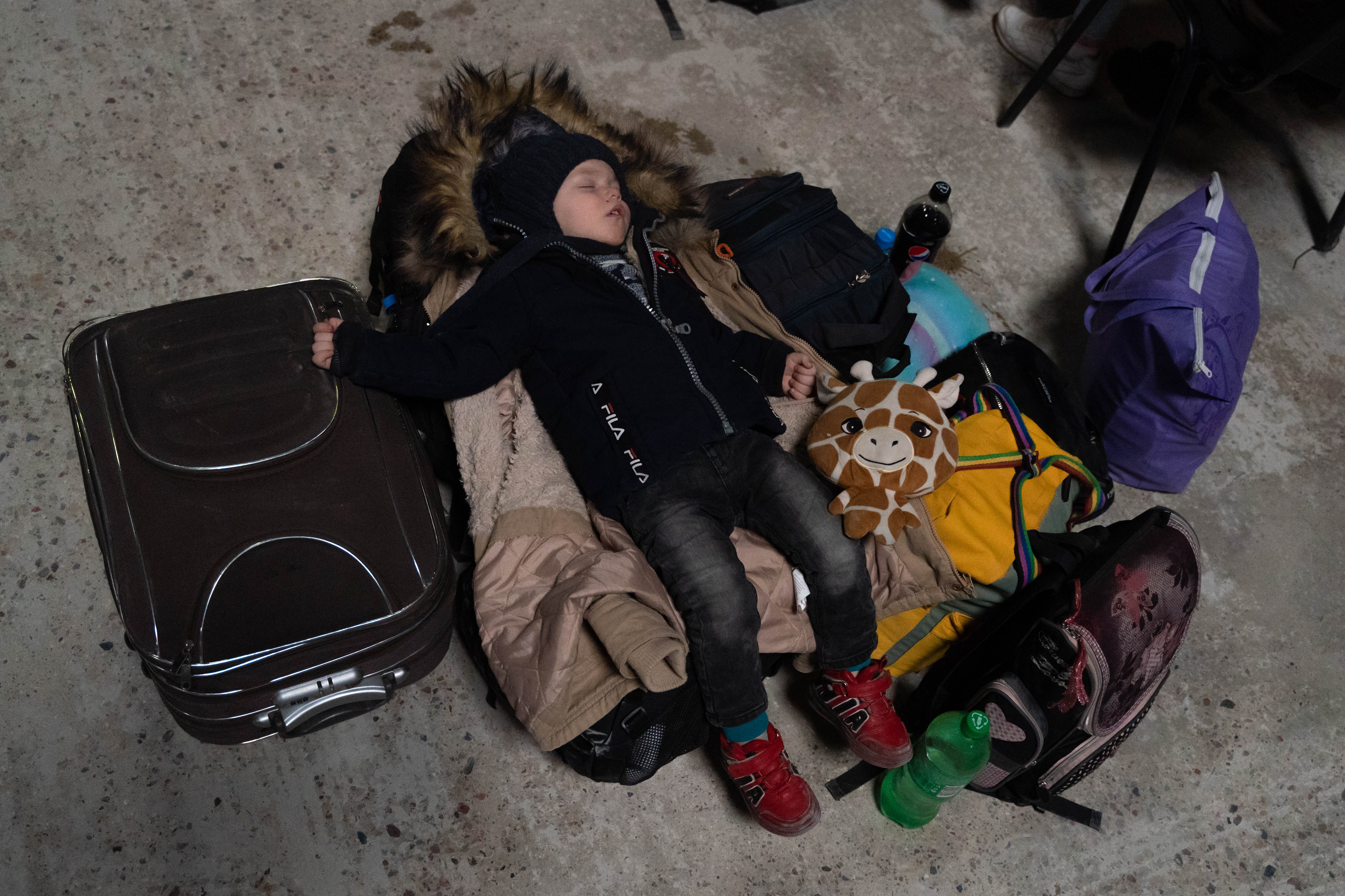 Un niño ucraniano duerme sobre las pertenencias de su madre