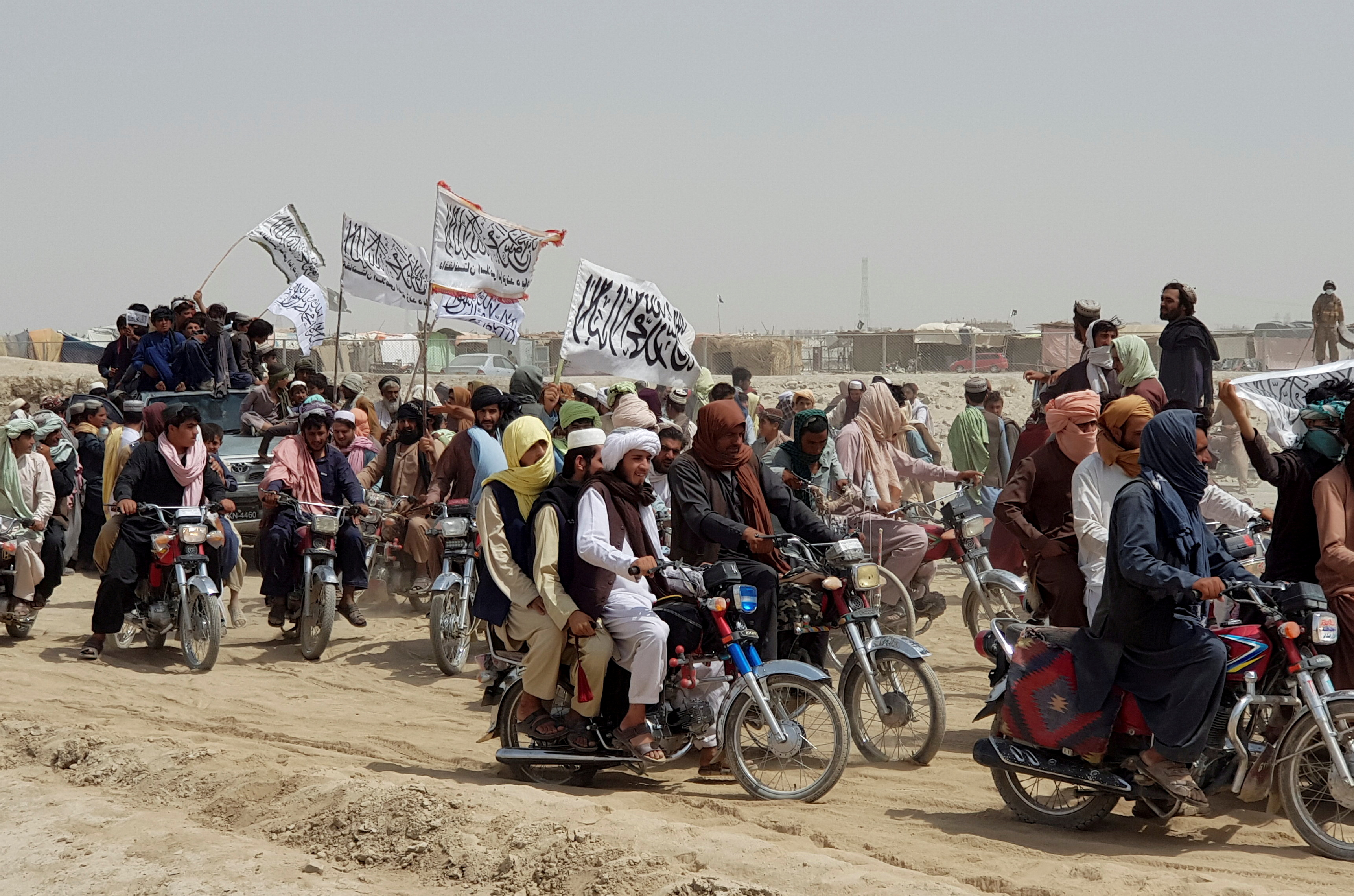 Personas en vehículos, sosteniendo banderas talibanas, se reúnen cerca del cruce de la Puerta de la Amistad en la ciudad fronteriza entre Pakistán y Afganistán de Chaman, Pakistán, 14 de julio de 2021. Fotografía tomada el 14 de julio de 2021. (REUTERS / Abdul Khaliq Achakzai)