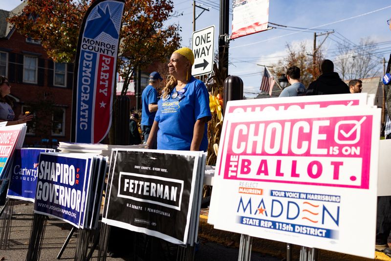 Un simpatizante reparte carteles antes de la parada del candidato demócrata a gobernador y fiscal general de Pensilvania, Josh Shapiro, en la gira 