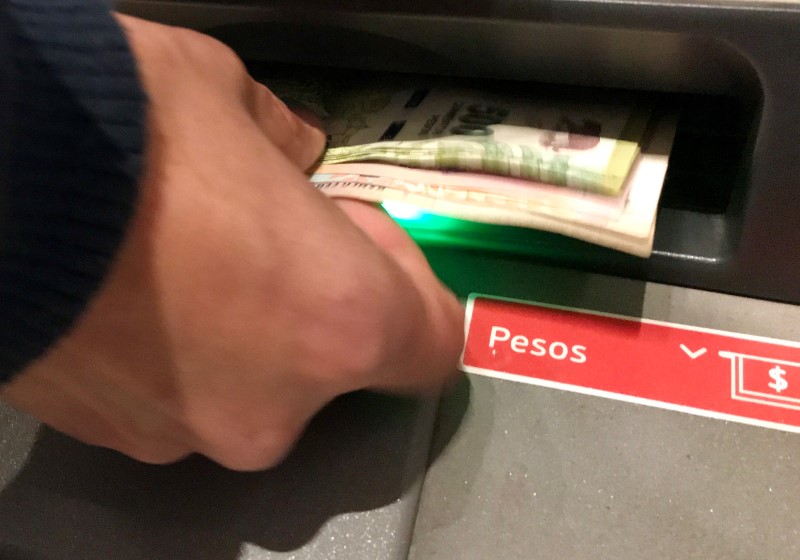 Una persona retira pesos de un cajero automático (Reuters)