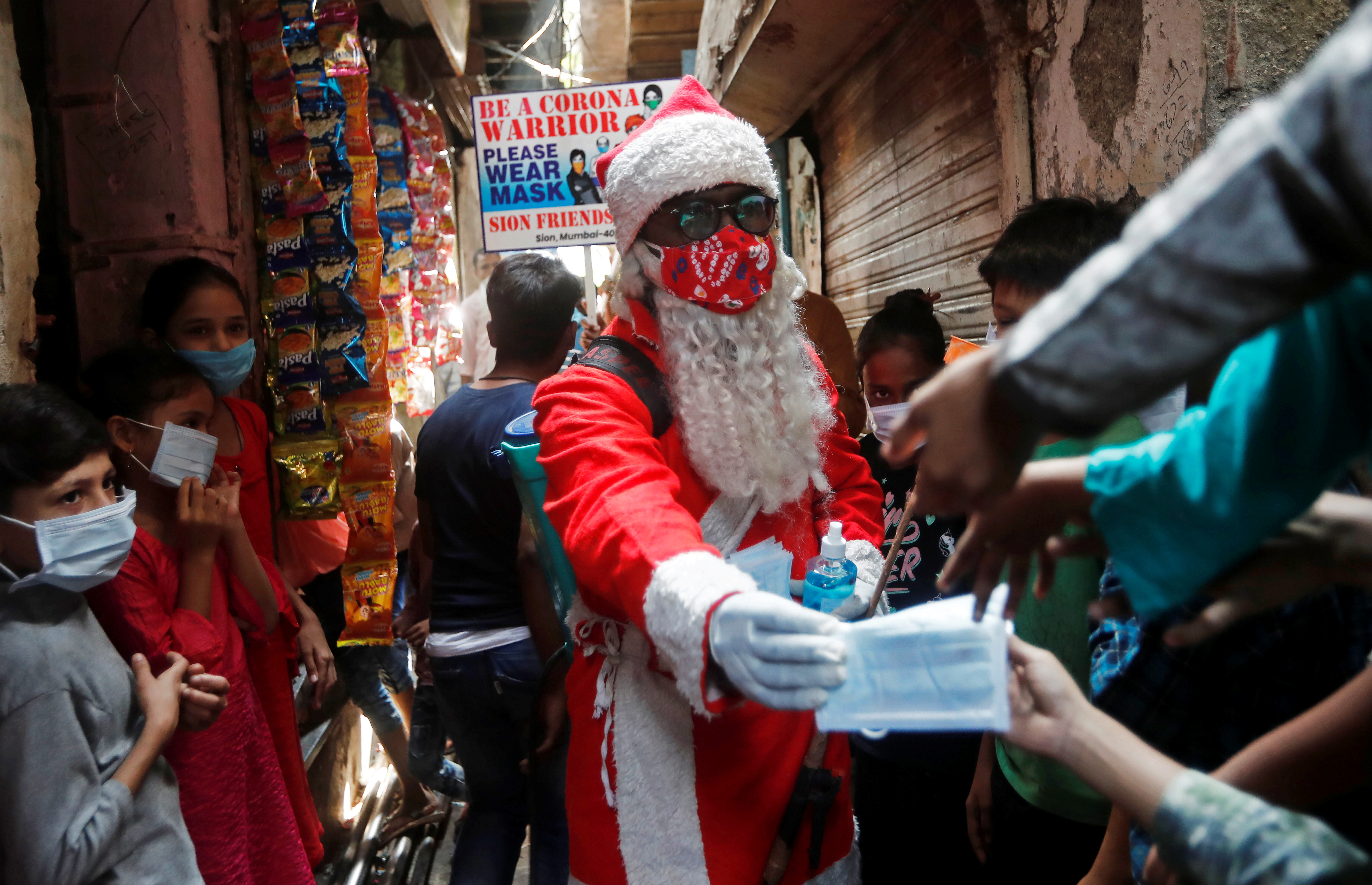 Un hombre con un disfraz de Papá Noel distribuye gratuitamente máscaras protectoras a los niños dentro de un barrio marginal en Mumbai, India (REUTERS/Francis Mascarenhas)