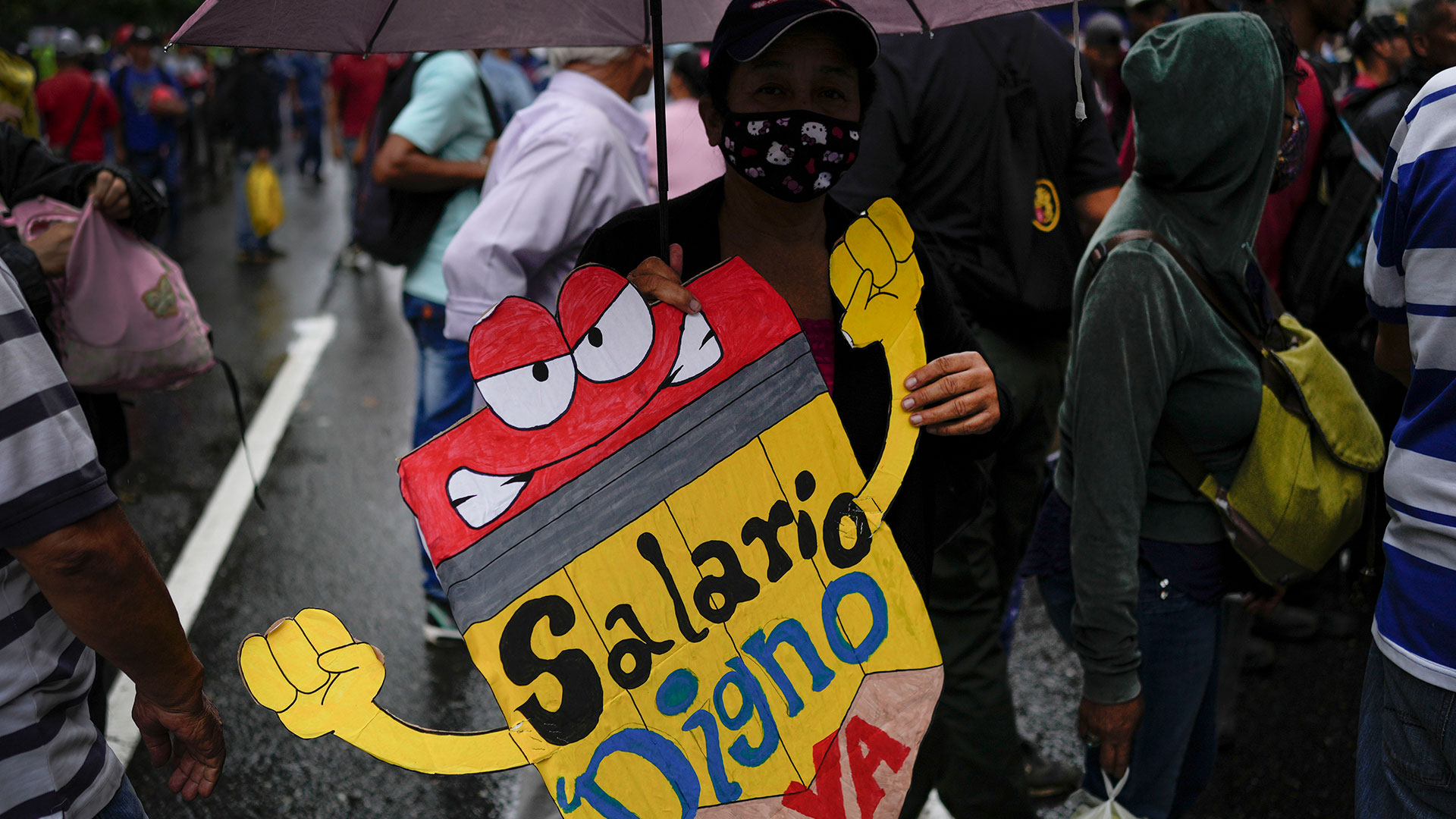 Un maestro sostiene un cartel durante una protesta de trabajadores públicos exigiendo que el gobierno pague sus beneficios completos y respete los convenios colectivos en Caracas, Venezuela, el miércoles 10 de agosto de 2022. (AP Foto/Matias Delacroix)