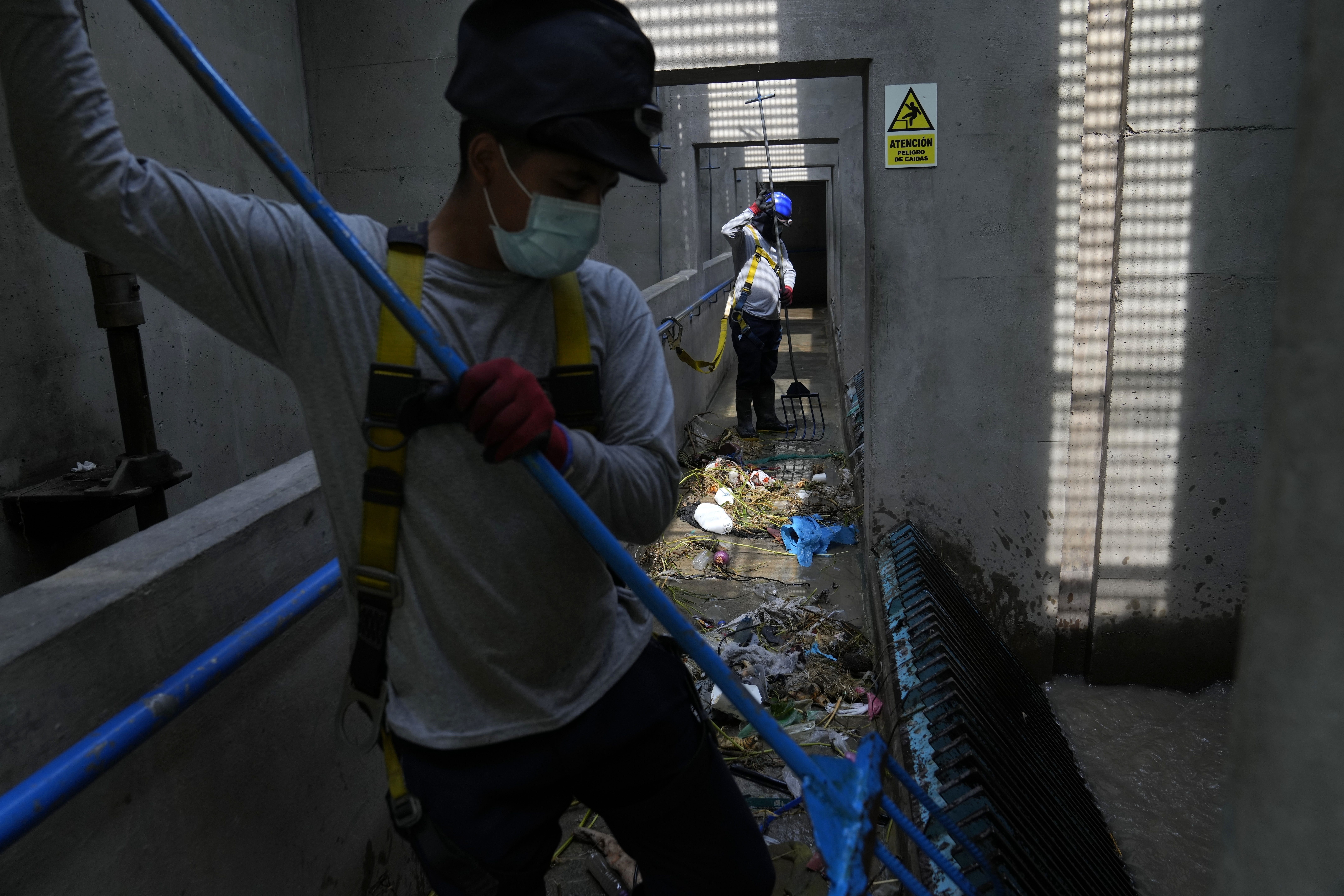 Operarios de tratamiento de aguas recopilan basura dentro de la planta de SEDAPAL, la empresa estatal de suministro de agua, en Lima, Perú, el 21 de marzo de 2023. (AP Foto/Martín Mejía)