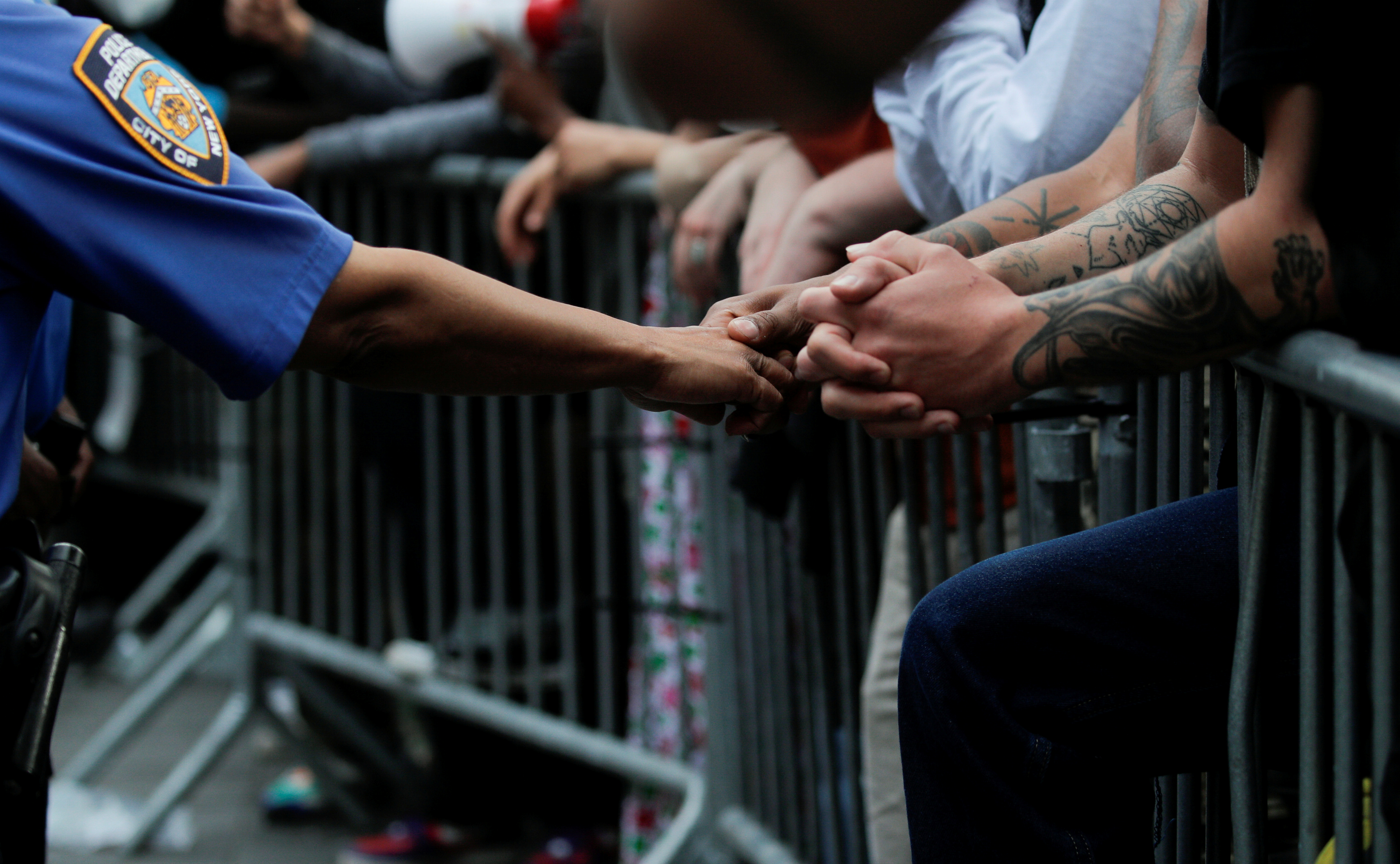 En contraste con la violencia de otras escenas, un policía estrecha la mano de un manifestante que está apoyado sobre una valla de contención en Brooklyn (REUTERS/Brendan McDermid)