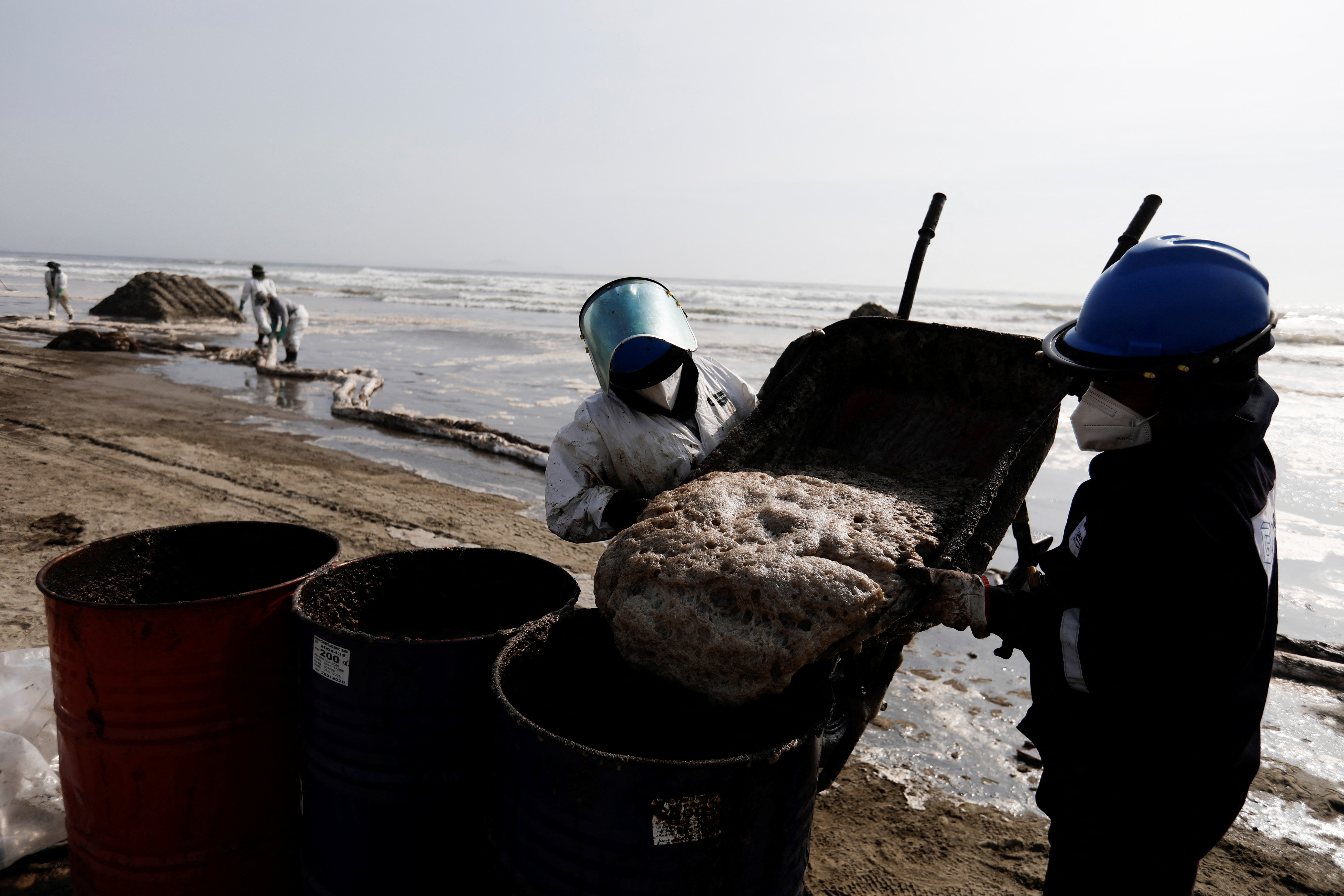 Workers clean an oil spill caused by abnormal waves, triggered by a massive underwater volcanic eruption in Tonga, off the coast of Lima, in Ventanilla, Peru, January 19, 2022.   REUTERS/Angela Ponce
