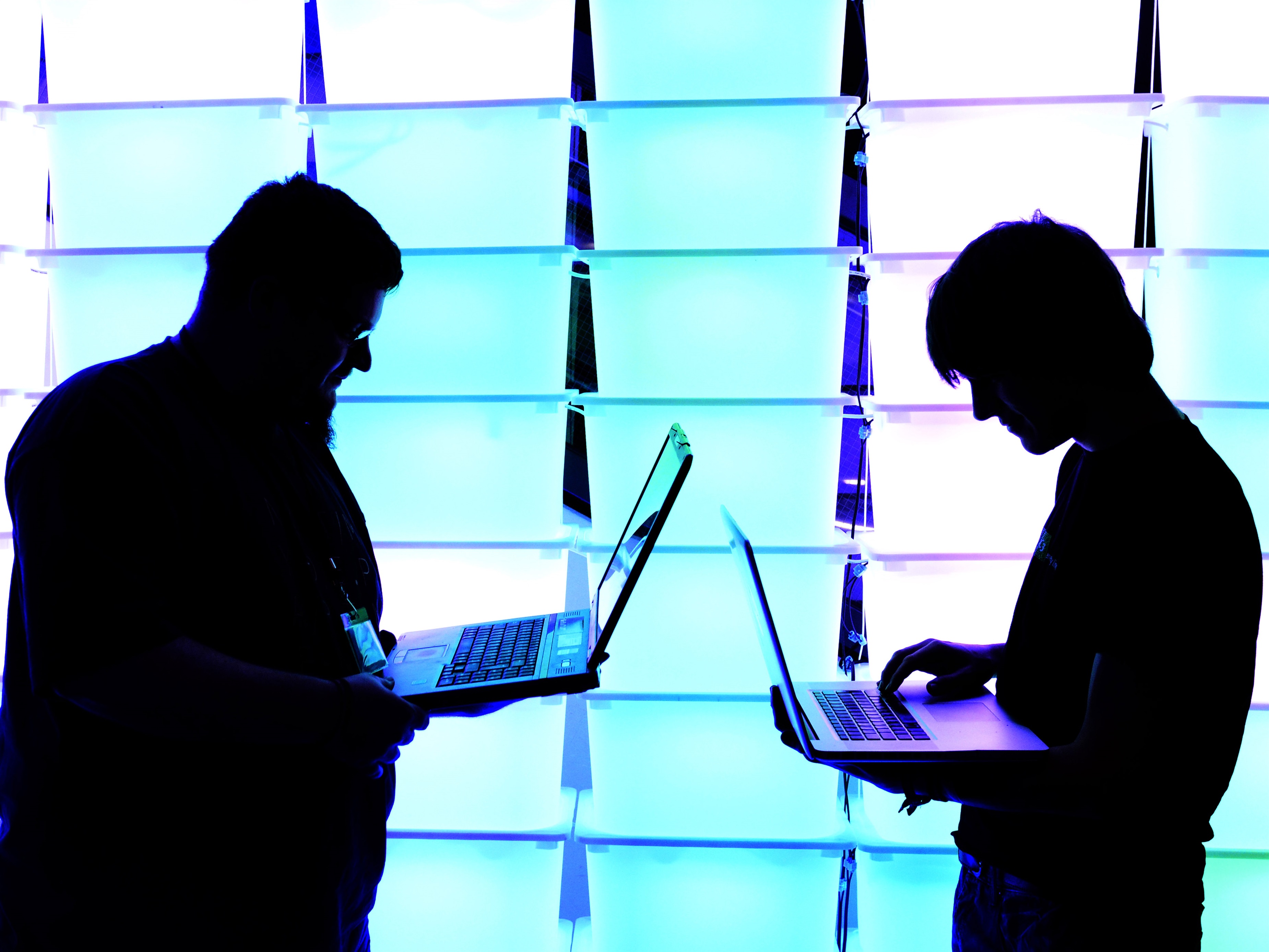 Participant hold their laptops in front of an illuminated wall at the annual Chaos Computer Club (CCC) computer hackers' congress, called 29C3, on December 28, 2012 in Hamburg, Germany.
