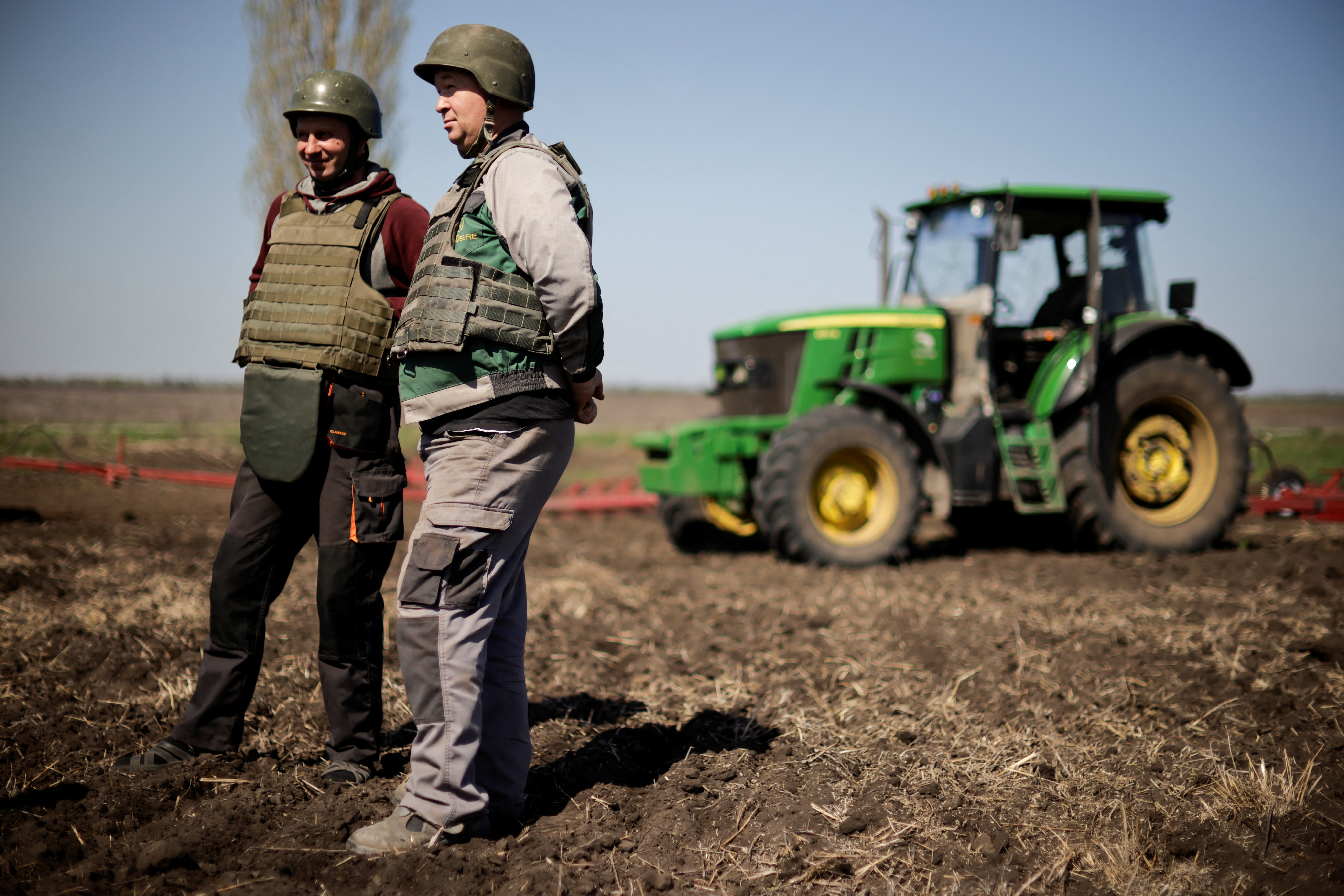 Yuri y Oleksiy, agricultores ucranianos que usan chalecos antibalas y cascos, trabajan en la capa superior del suelo en un campo, en medio de la invasión rusa de Ucrania, en la región de Zaporizhzhia, Ucrania, 26 de abril de 2022. REUTERS/Ueslei Marcelino
