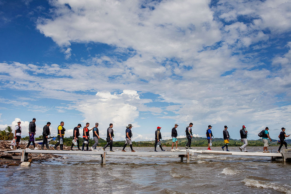 Migrantes abordan un barco turístico para cruzar el Golfo de Urabá hacia Capurganá, en Necoclí, Colombia, el 26 de julio de 2022 (Thomson Reuters Foundation/Fabio Cuttica)