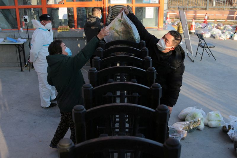 Un trabajador entrega alimentos en un complejo residencial bajo confinamiento luego de un brote de COVID-19 en Xian, provincia de Shaanxi, China. (cnsphoto via REUTERS)