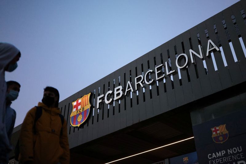 FOTO ARCHIVO: Unas personas pasan junto al logotipo del club de fútbol Barcelona en el exterior del estadio Camp Nou en Barcelona