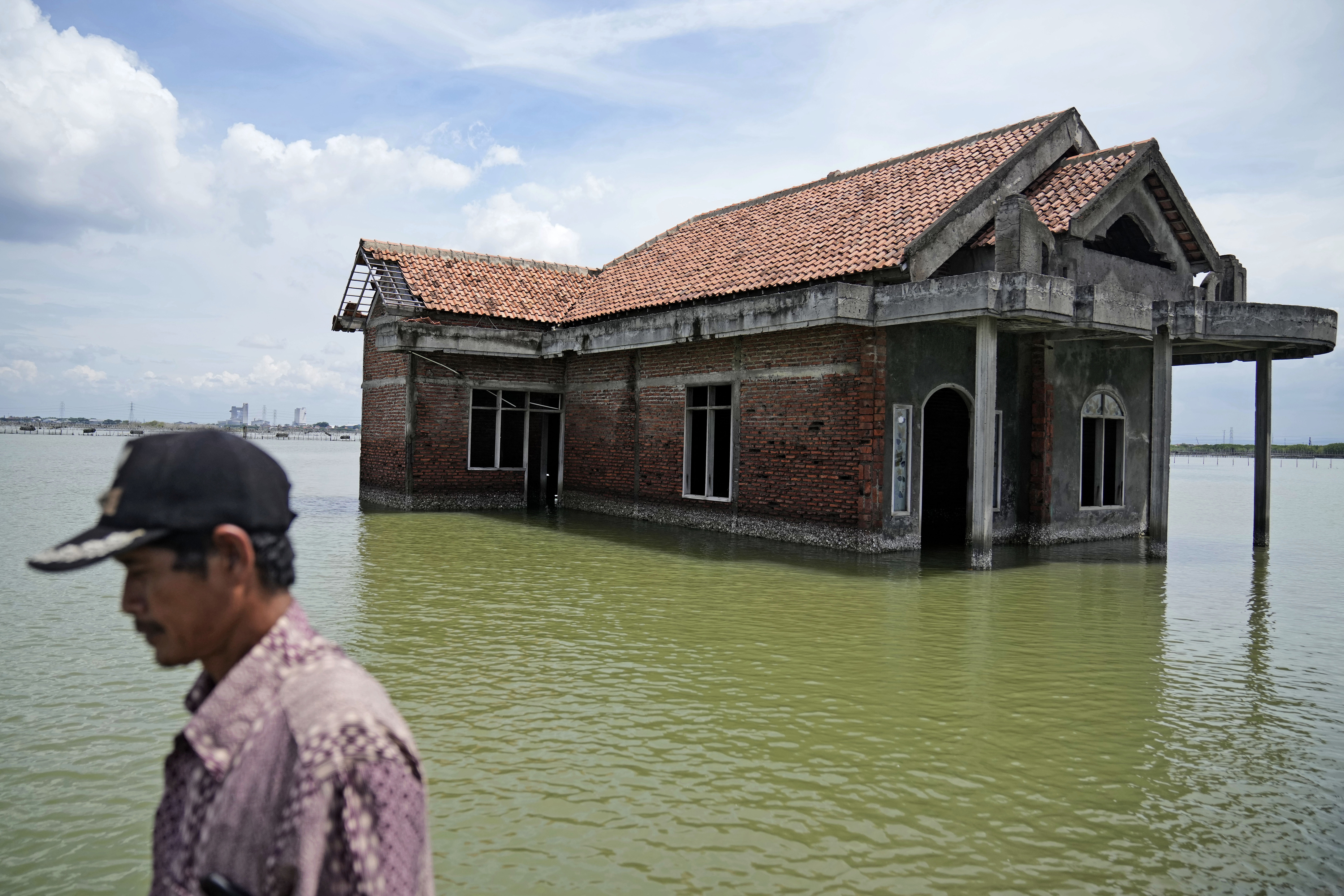 Un hombre pasa frente a una casa abandonada después de que se inundara debido al aumento del nivel del mar en Sidogemah, Java Central, Indonesia (AP /Dita Alangkara)