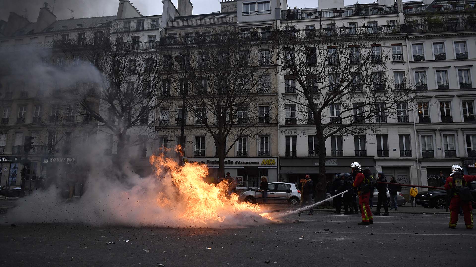 Un bombero apaga el fuego durante una manifestación de kurdos en París (AFP)