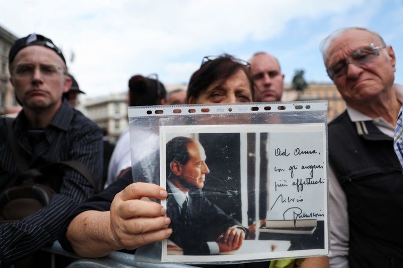 Una persona sostiene una foto de Silvio Berlusconi (REUTERS/Yara Nardi)